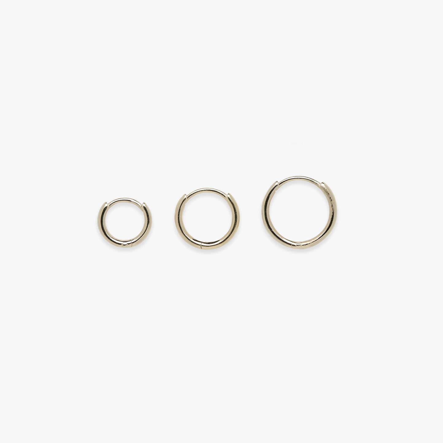 Three gold hoop earrings on a white background