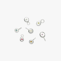 A collection of six Club Organique birthstone pendants in recycled sterling silver, each featuring a different color semi-precious gemstone set in a circular design, displayed against a white background.