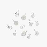 A collection of silver personalized charms with various designs, including initial letters and zodiac symbols, displayed on a white background.
