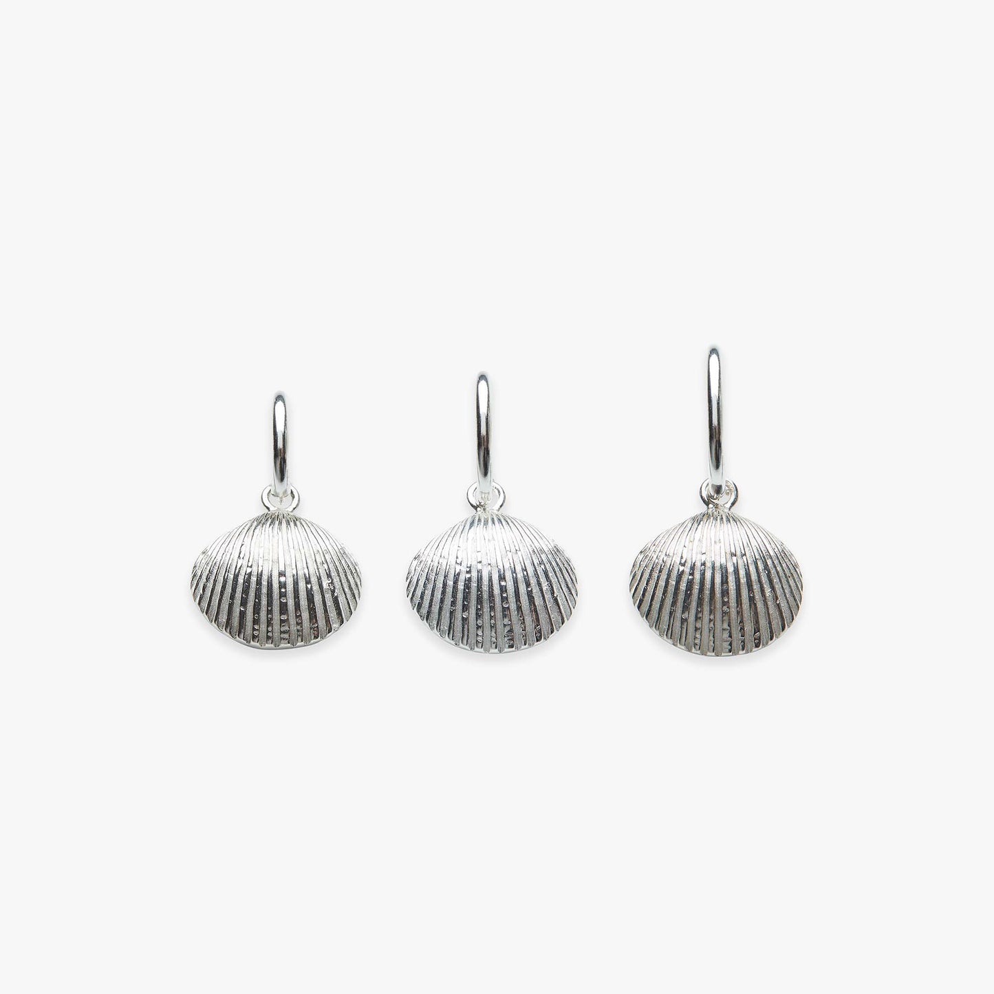 Three silver shell-shaped earrings on a white background