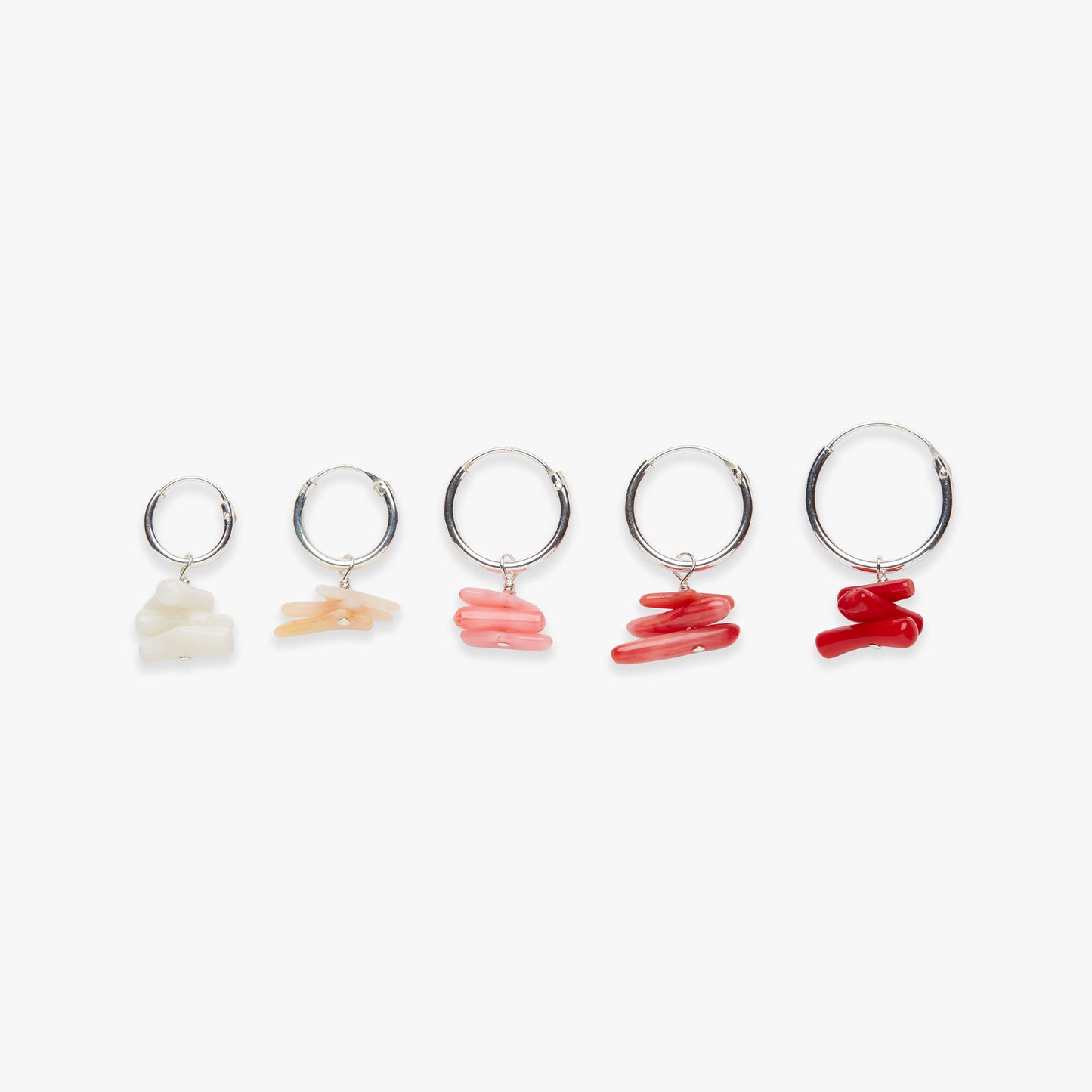 Set of five silver hoop earrings with different colored stones on a white background