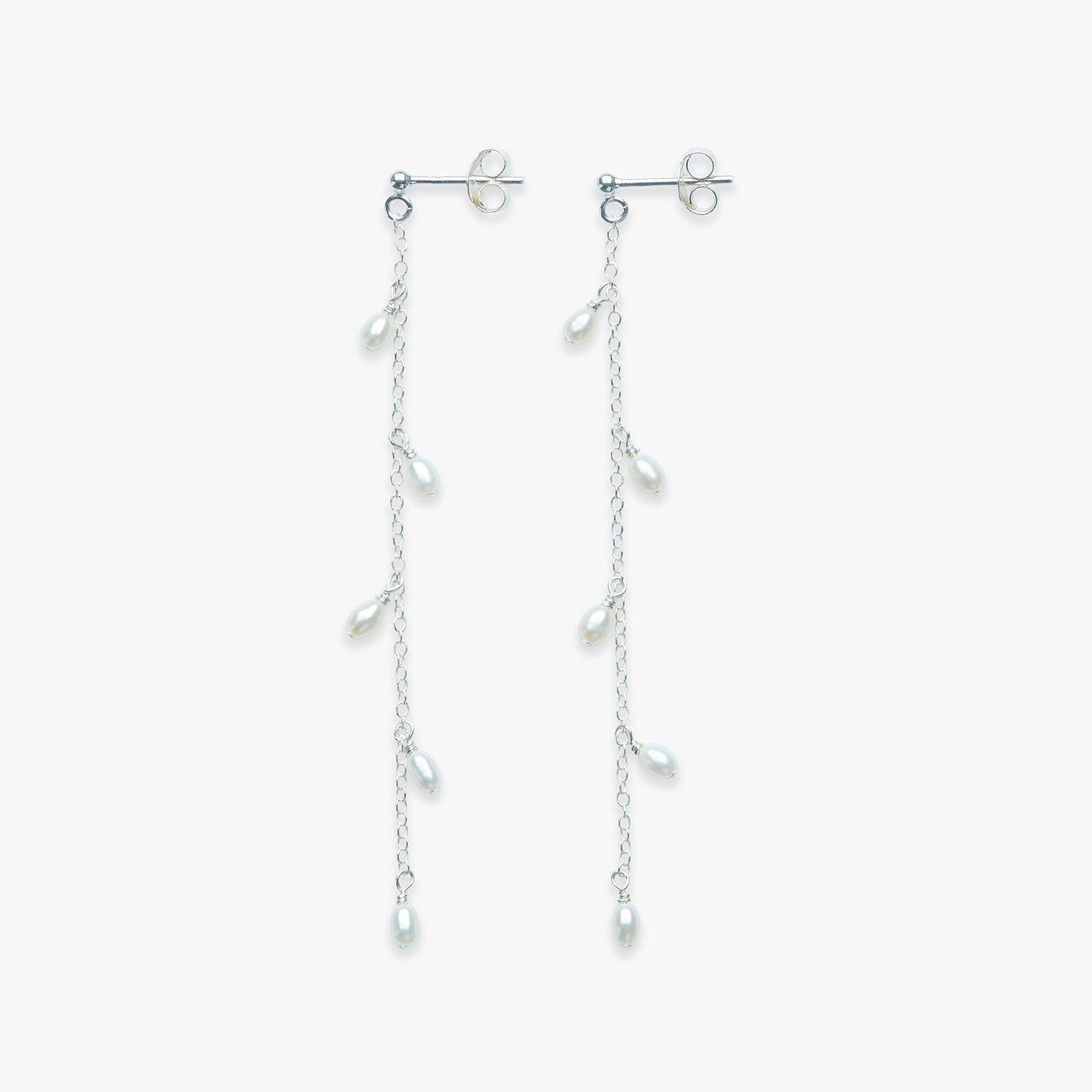 Pair of silver earrings with dangling pearls on a white background