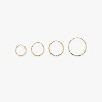 Set of four gold hoop earrings on a white background