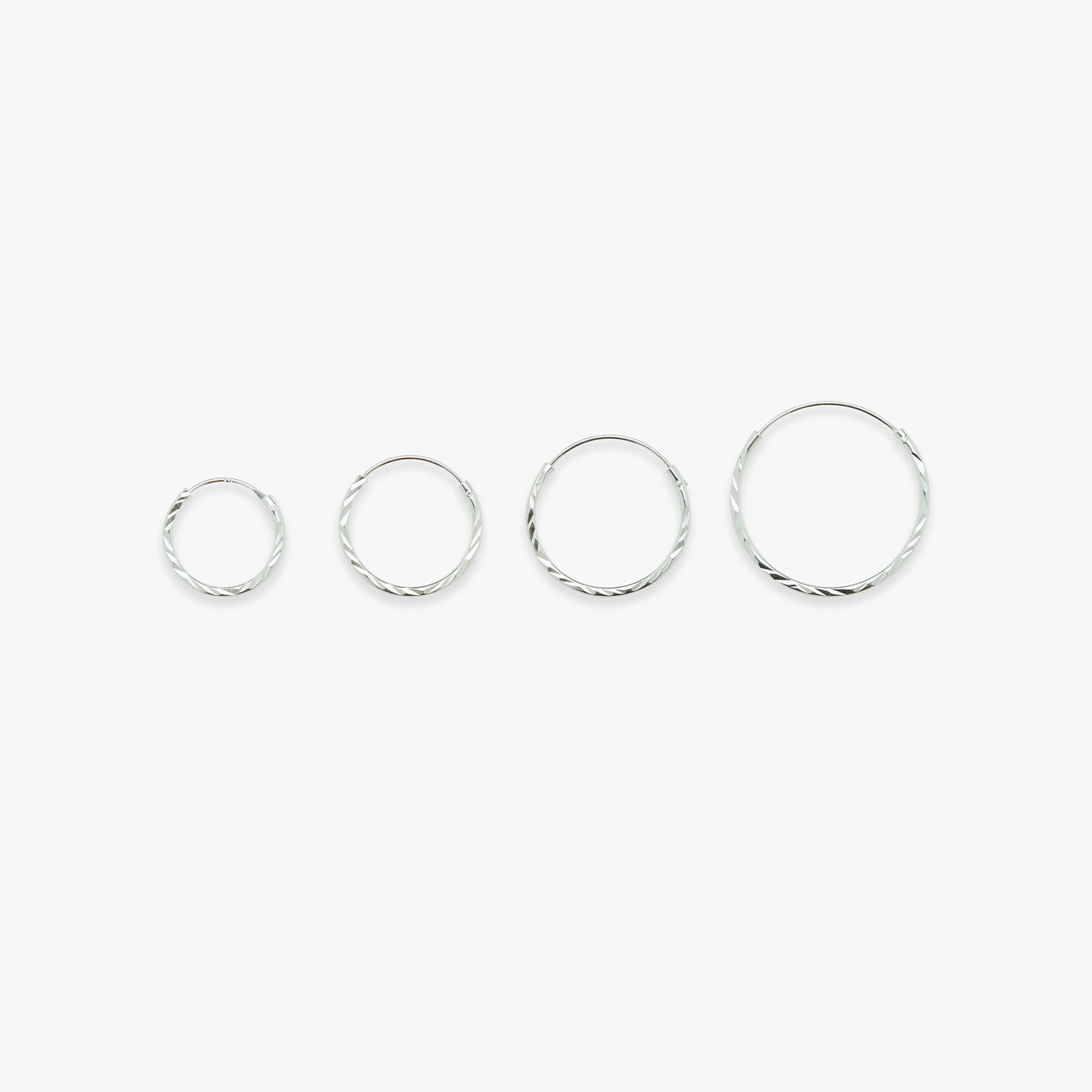Set of four silver hoop earrings on a white background