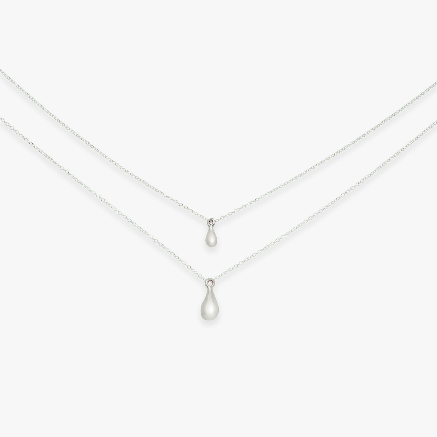 Two teardrop pendants on silver chains against a white background