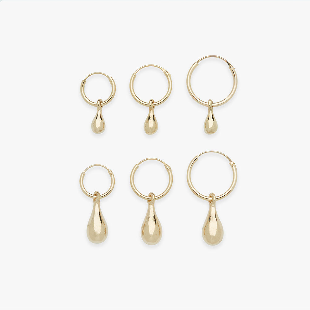 Set of gold hoop earrings with teardrop pendants on a white background