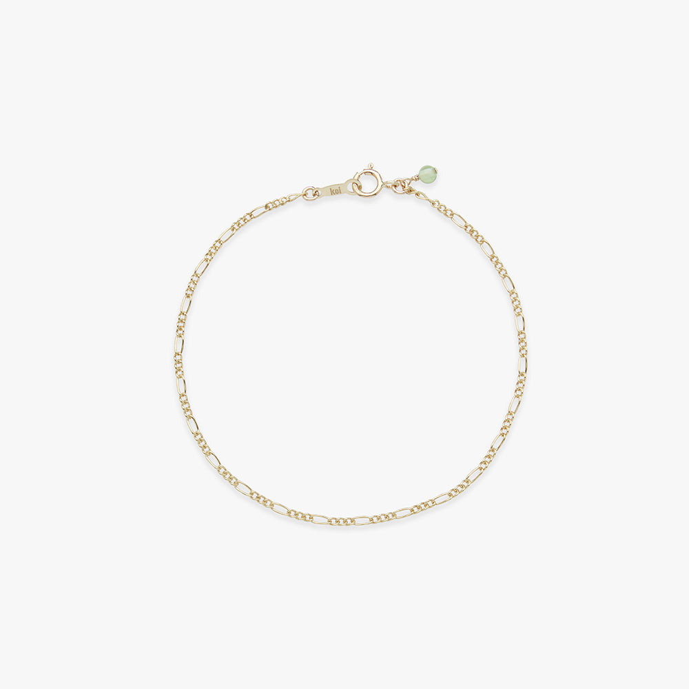 Gold bracelet with a green gemstone on a white background