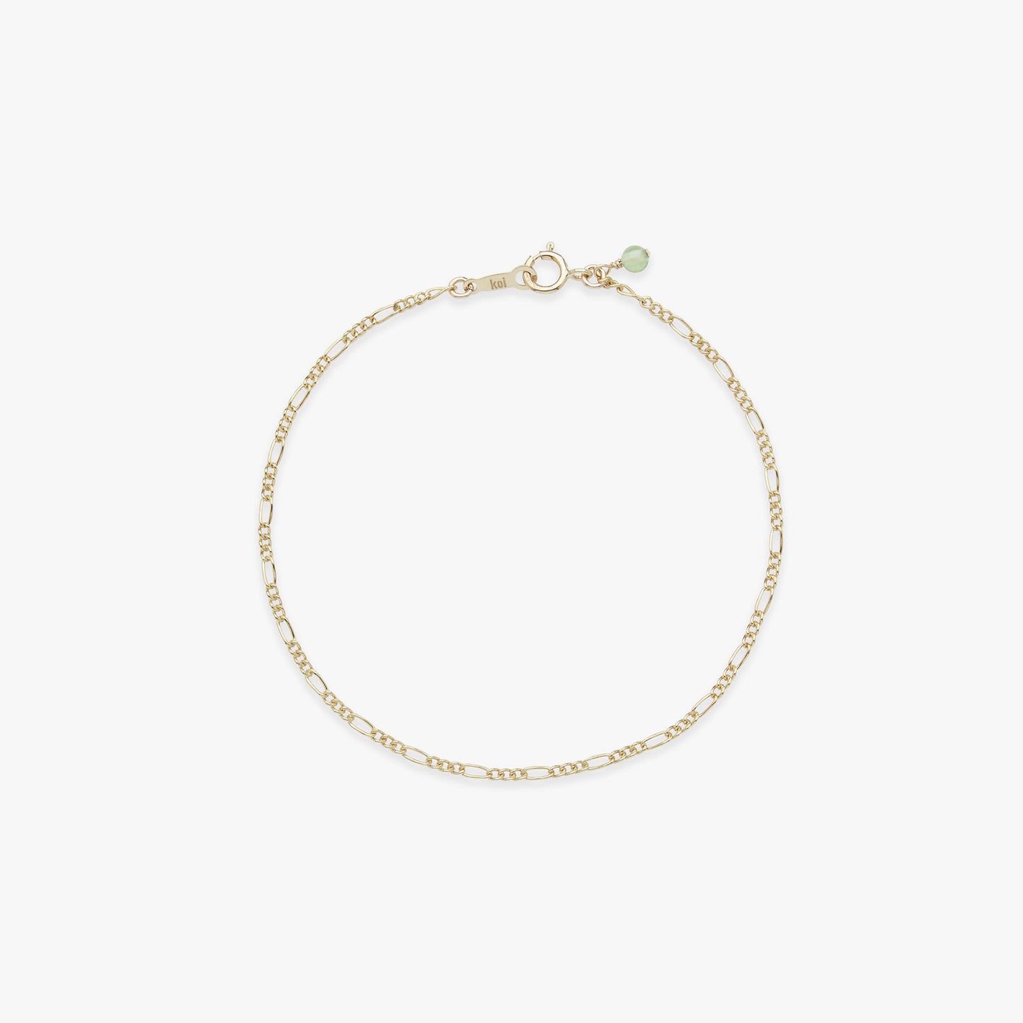 Gold bracelet with a green gemstone on a white background