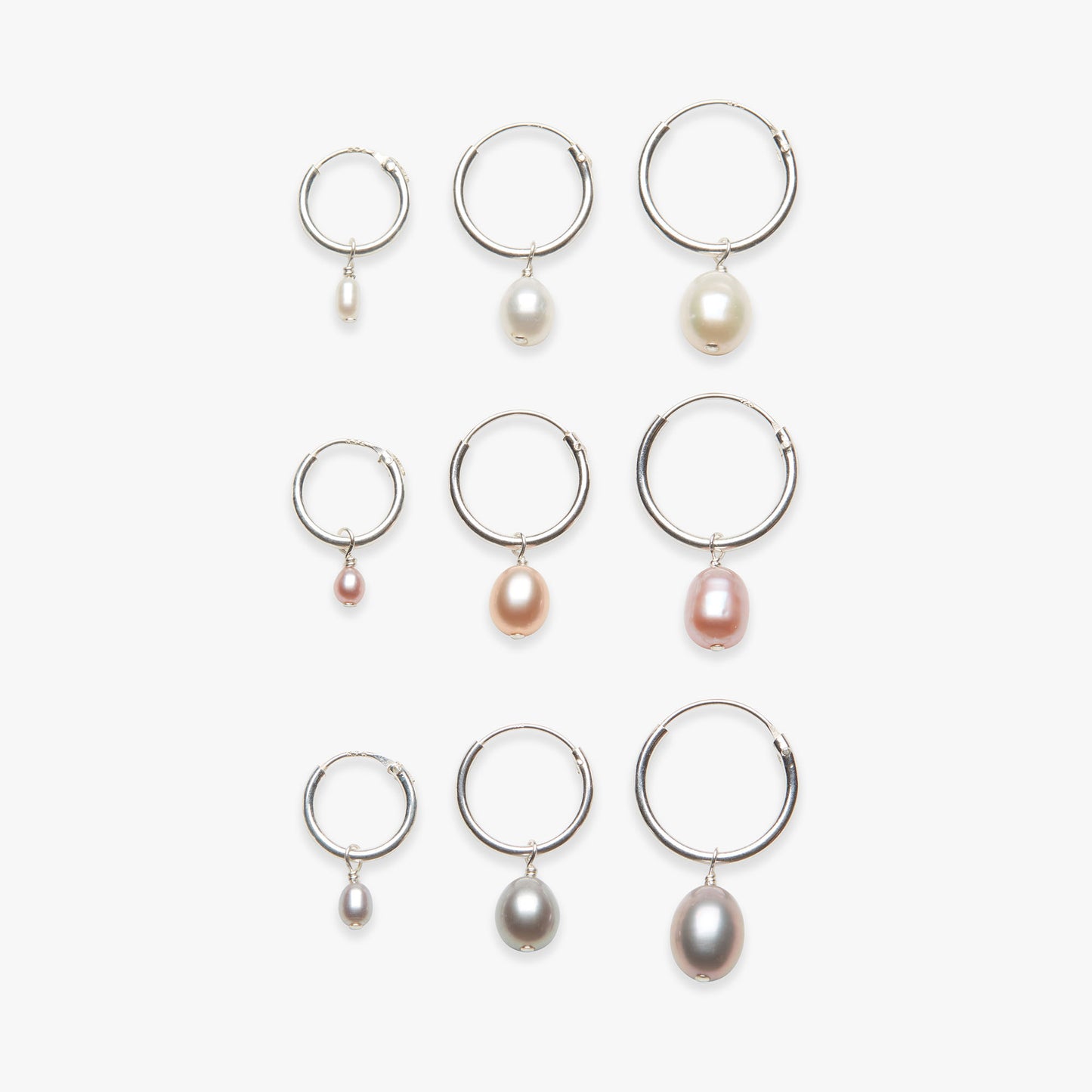 Set of silver hoop earrings with pearl drops on a white background