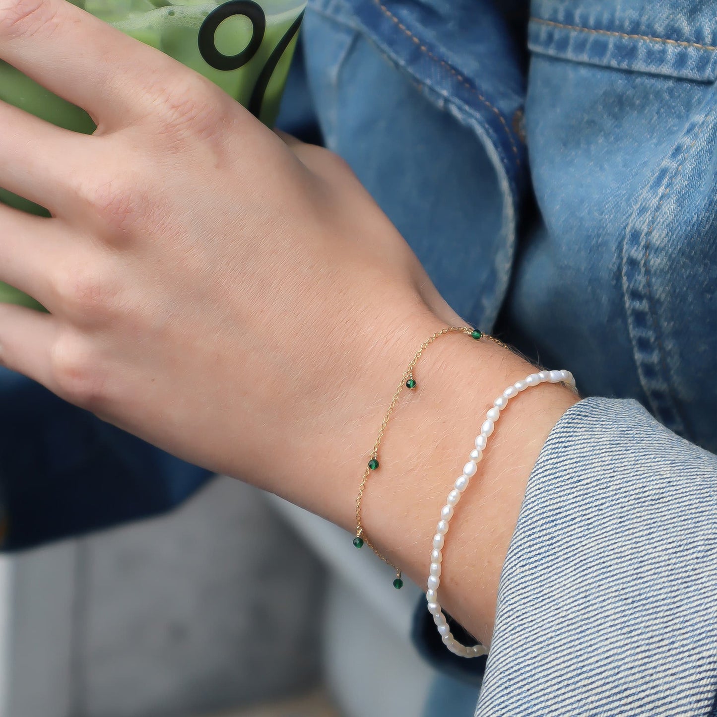 Close-up of a person's wrist wearing two bracelets with a blurred background