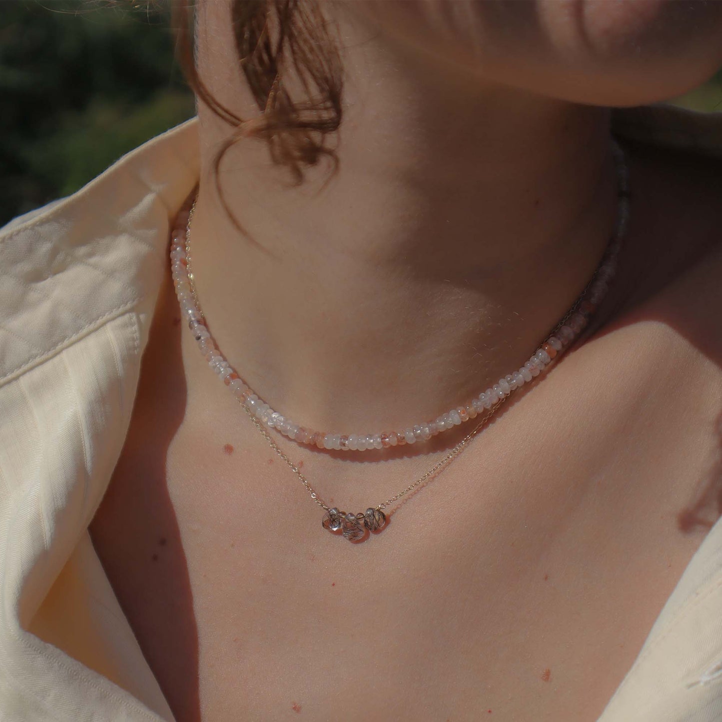 Close-up of a person wearing a delicate necklace with a blurred background
