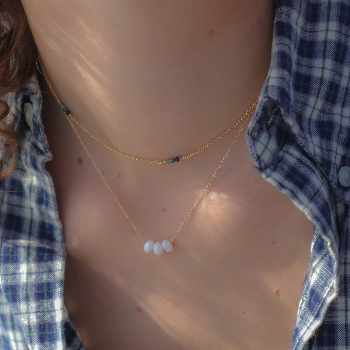 Necklace with blue beads worn by a person in a plaid shirt