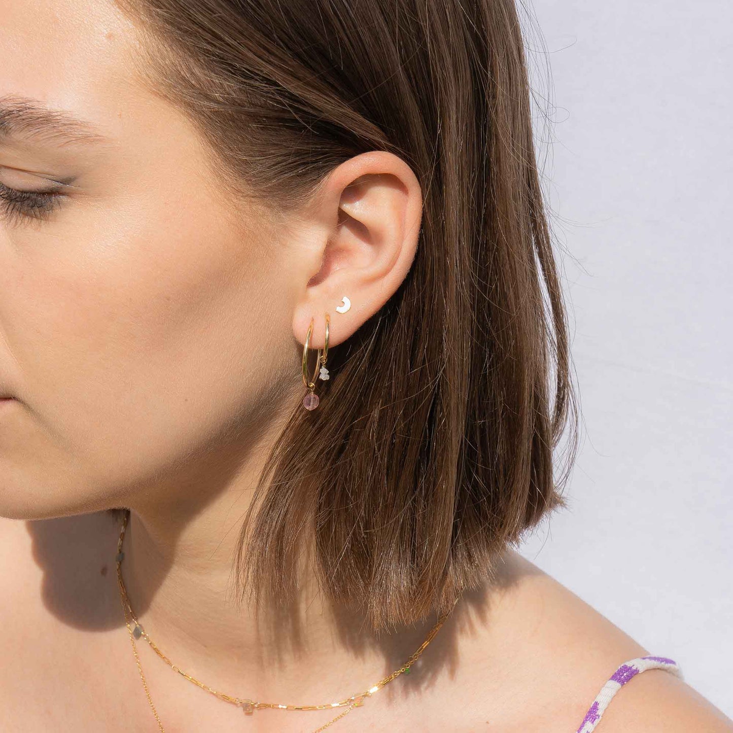 Close-up of a woman wearing earrings with a plain background