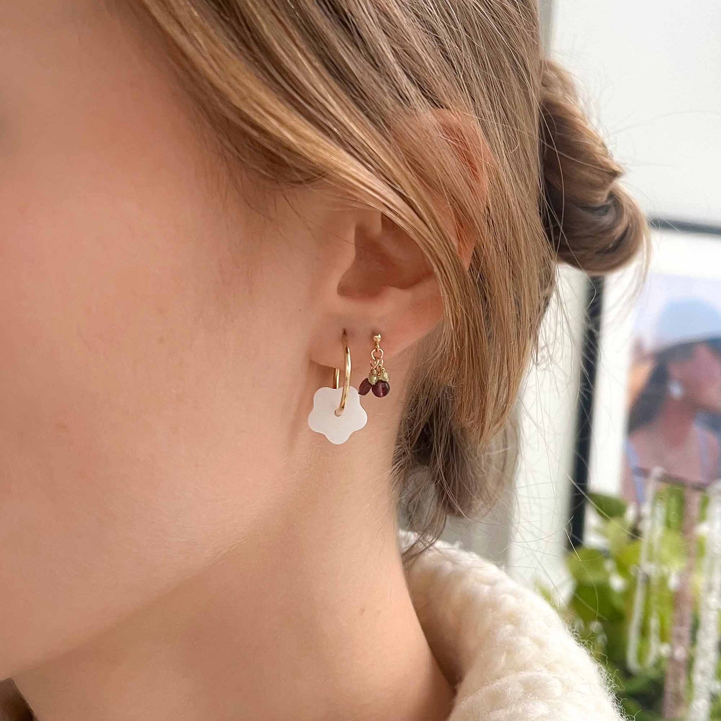 Close-up of a person wearing floral earrings with a blurred background