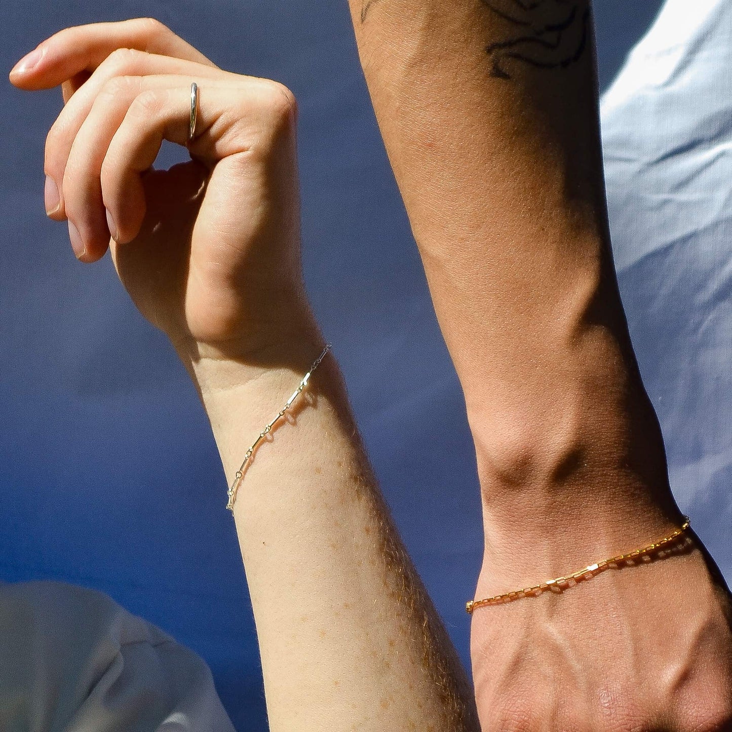 Close-up of a person's arm with a gold bracelet against a blue background