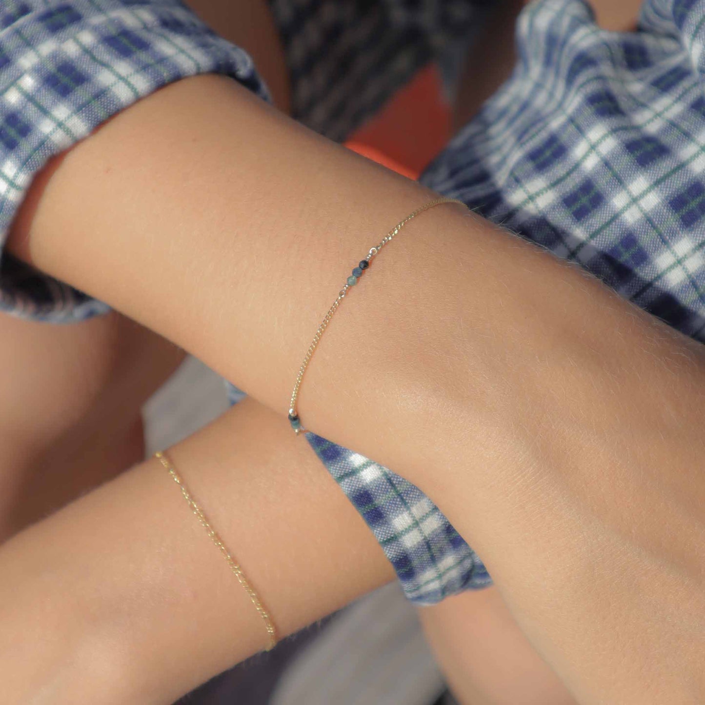 Close-up of a person's arm wearing two delicate gold bracelets.