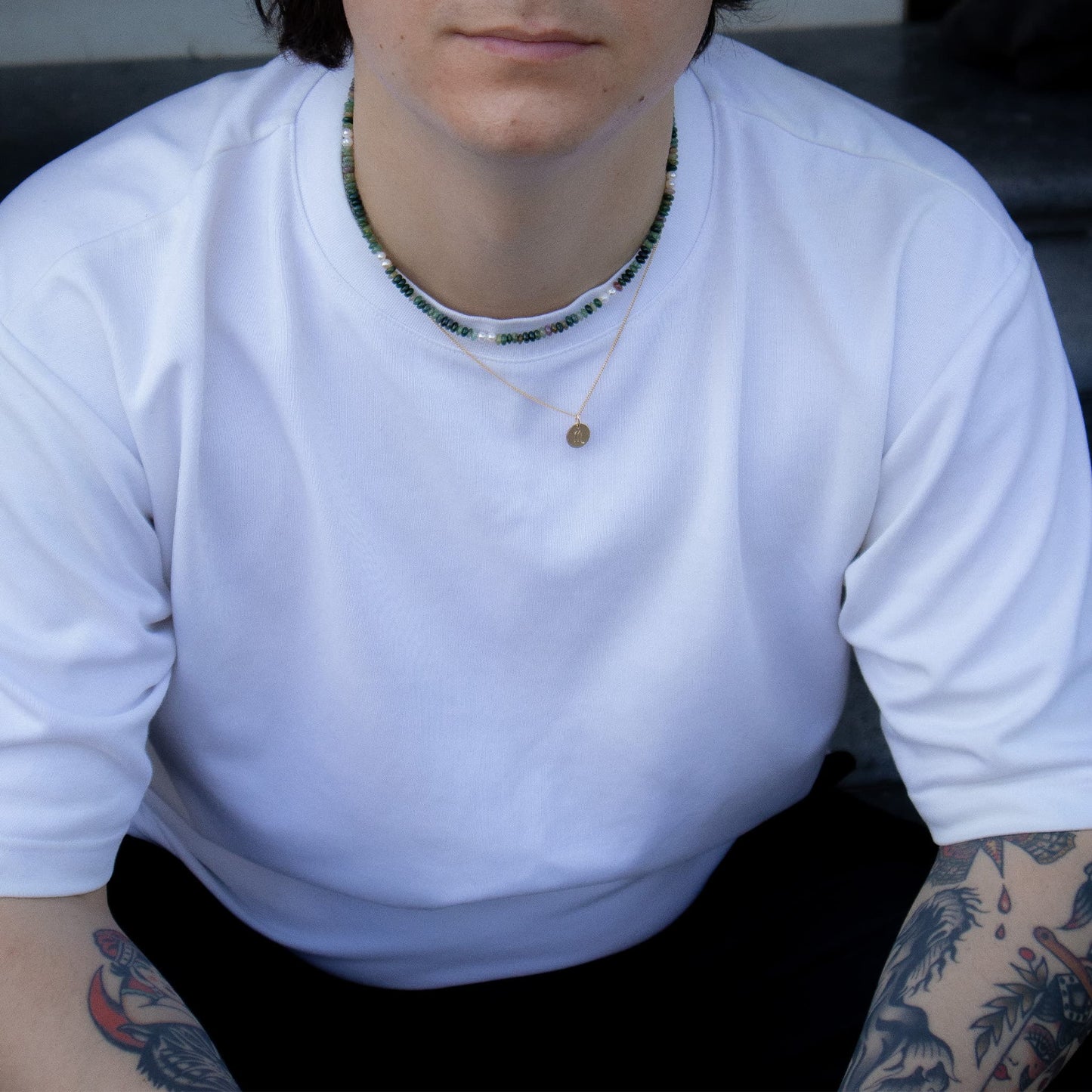 Person wearing a white long-sleeve shirt with visible tattoos on arms