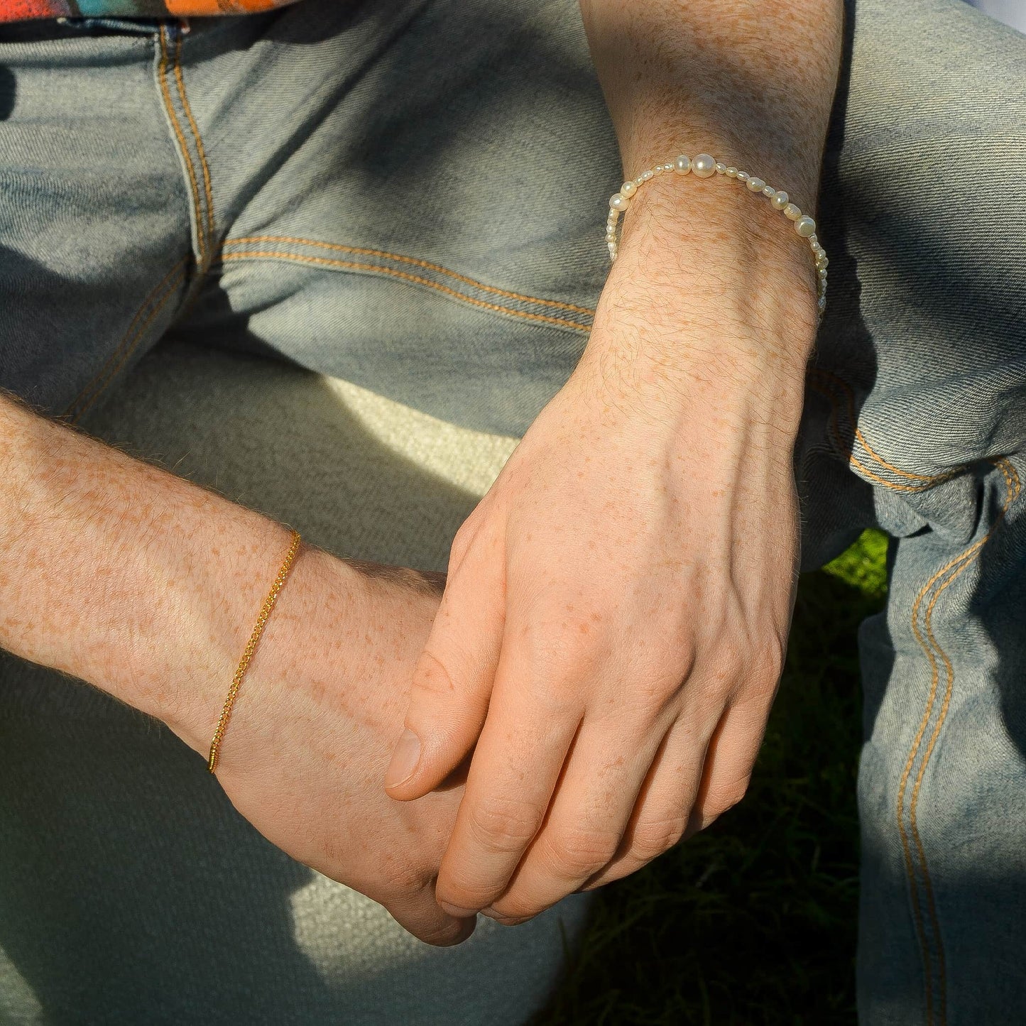 Close-up of a person's hands clasped together with denim jeans.