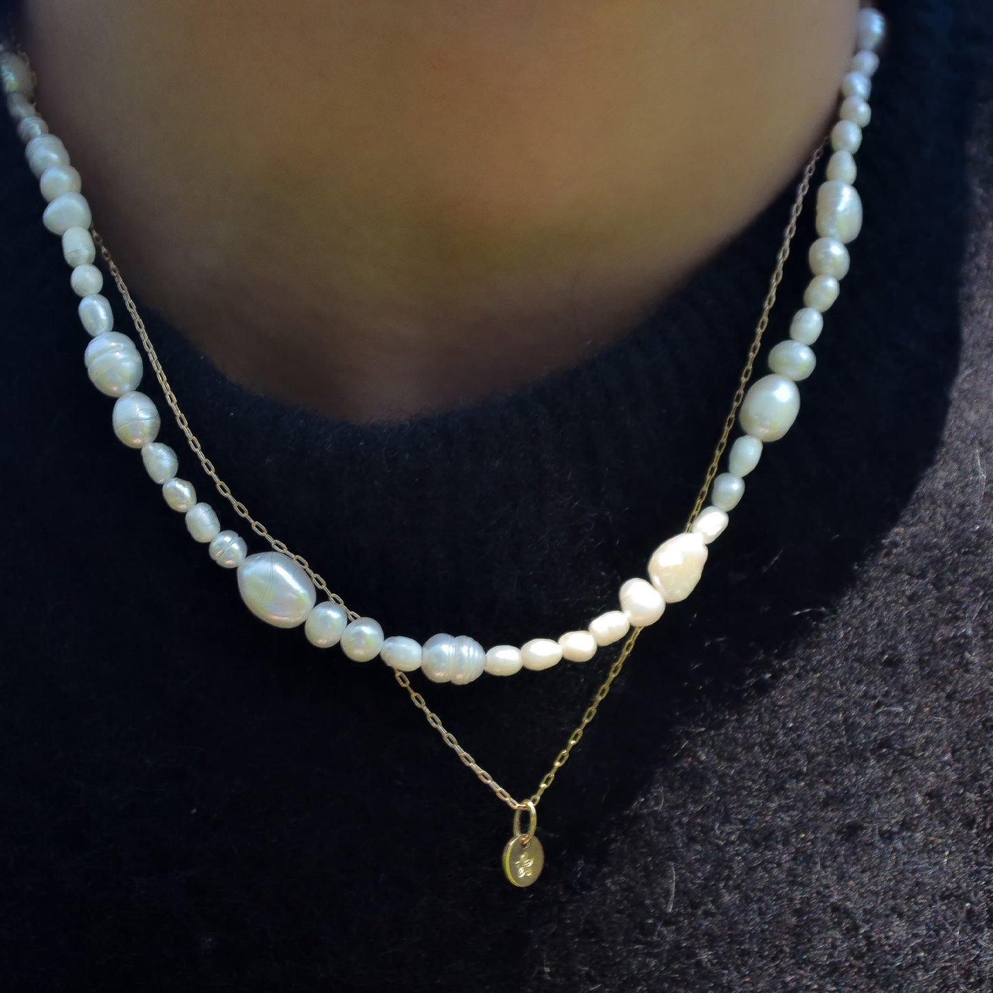 Pearl necklace with a gold chain and pendant on a dark background
