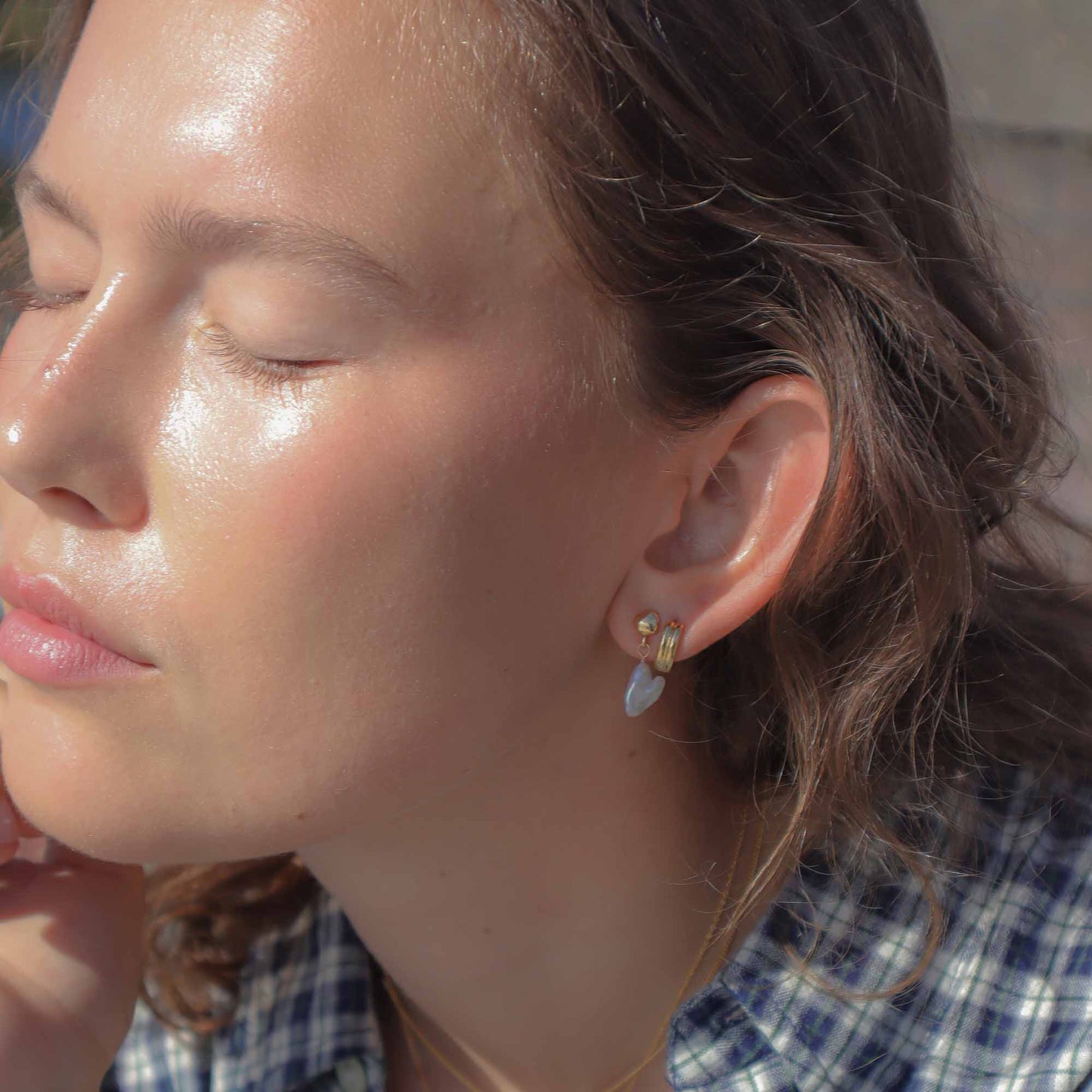 Close-up of a woman wearing earrings with sunlight on her face