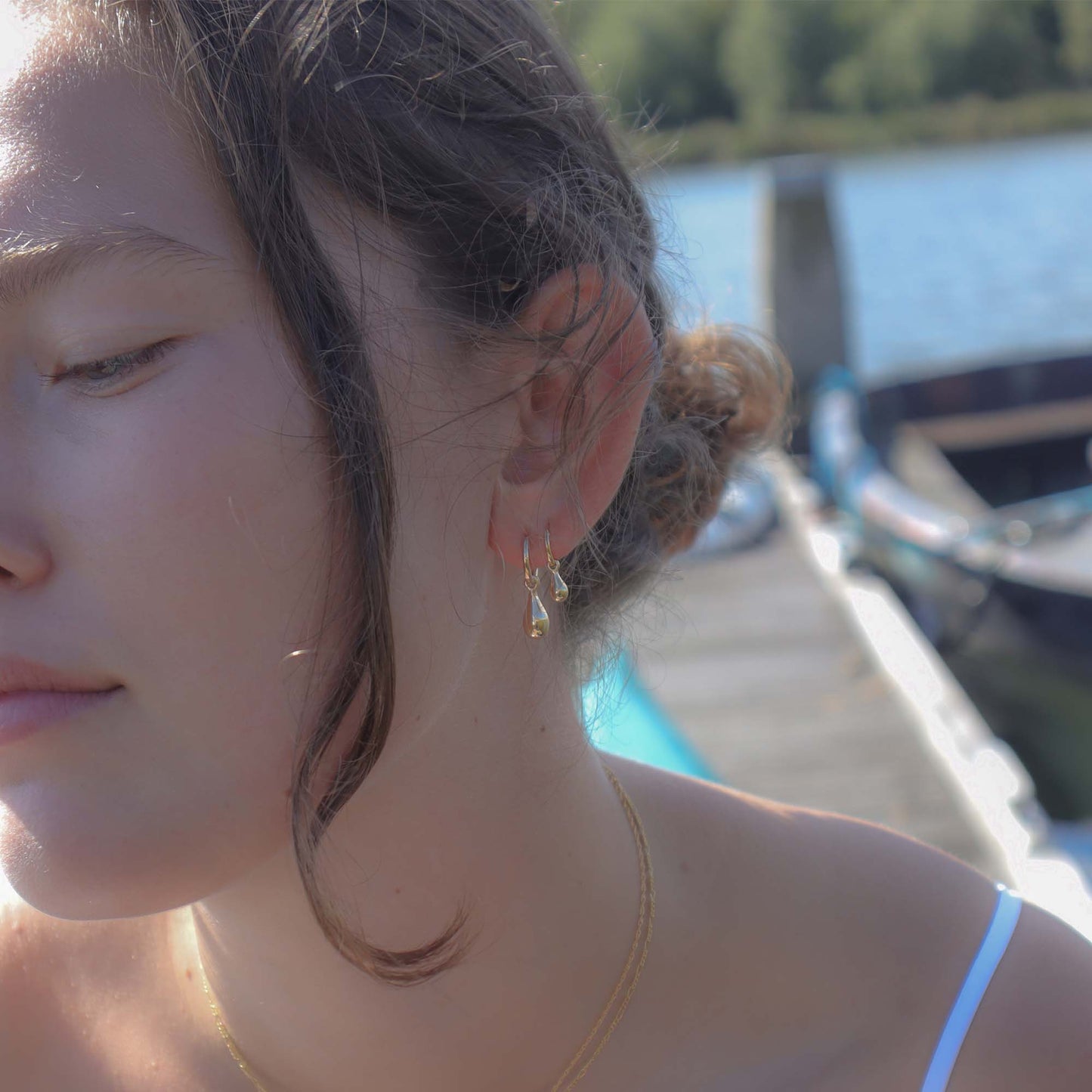 Close-up of a person with earrings by a body of water