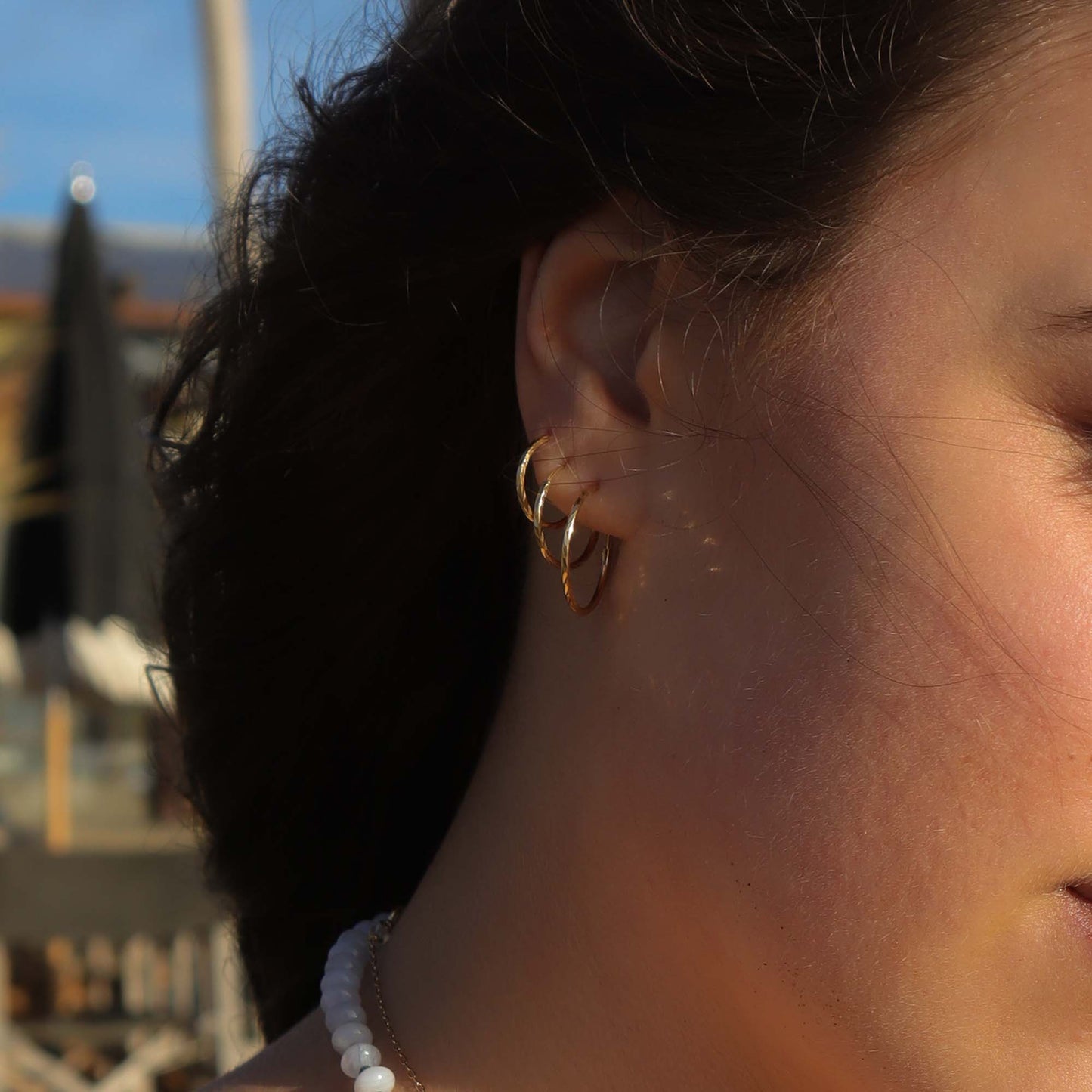 Close-up of a person wearing gold hoop earrings with a blurred background