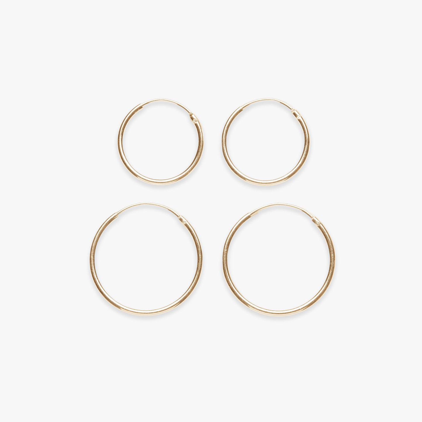 Four gold hoop earrings on a white background
