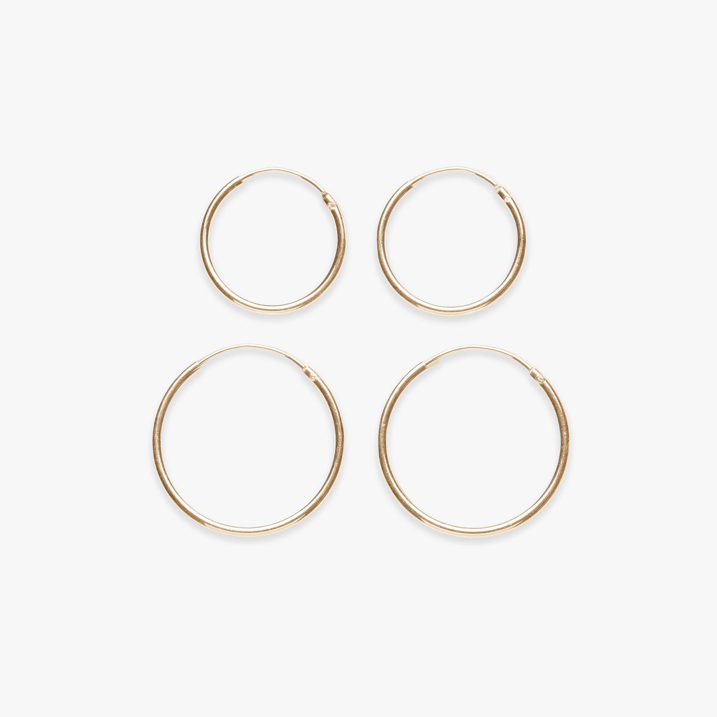 Four gold hoop earrings on a white background