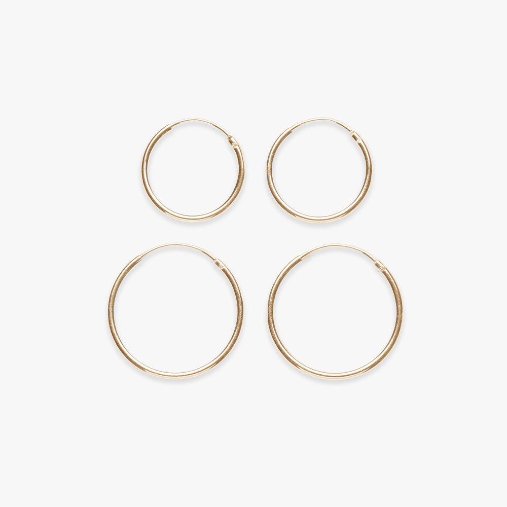Four gold hoop earrings on a white background
