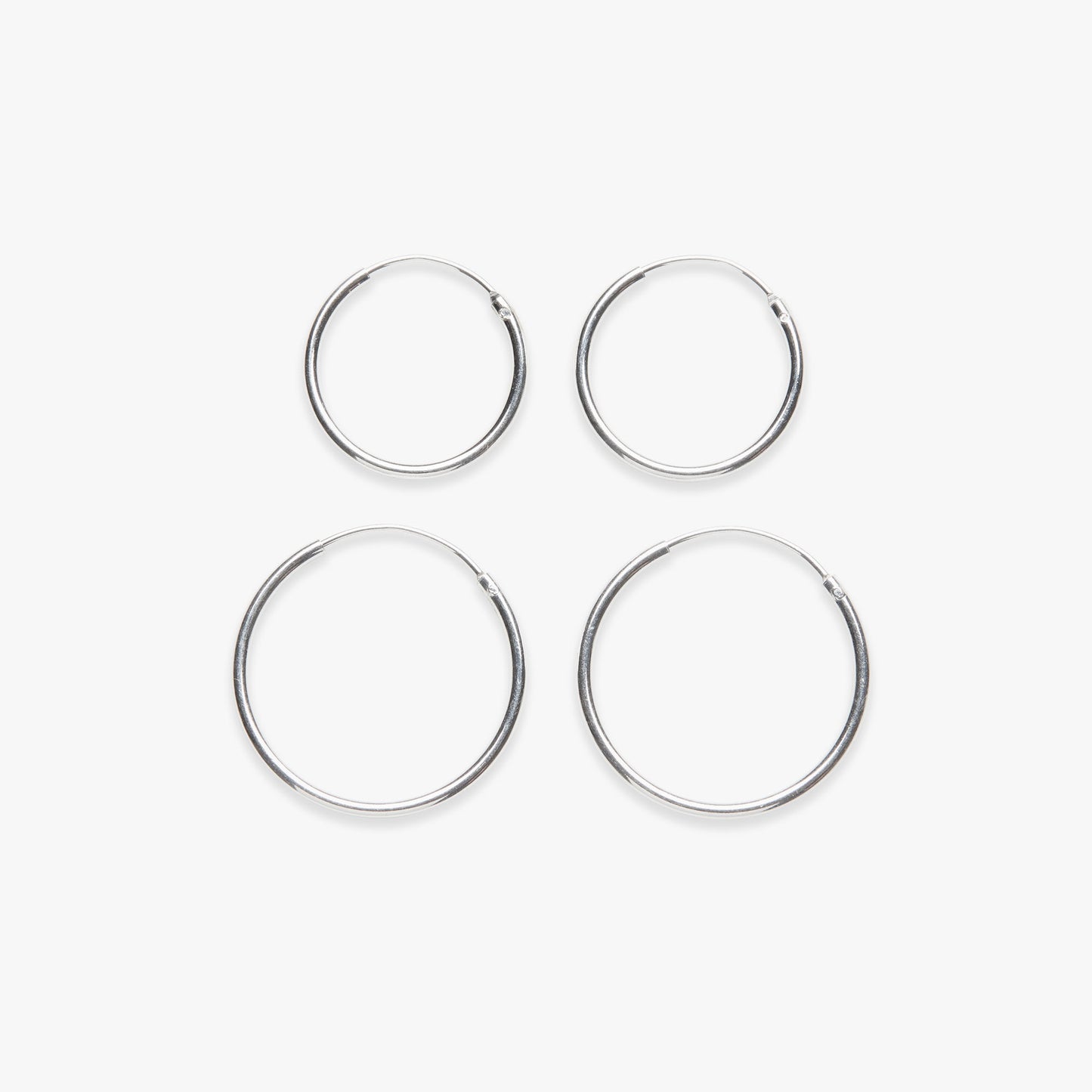 Four silver hoop earrings on a white background
