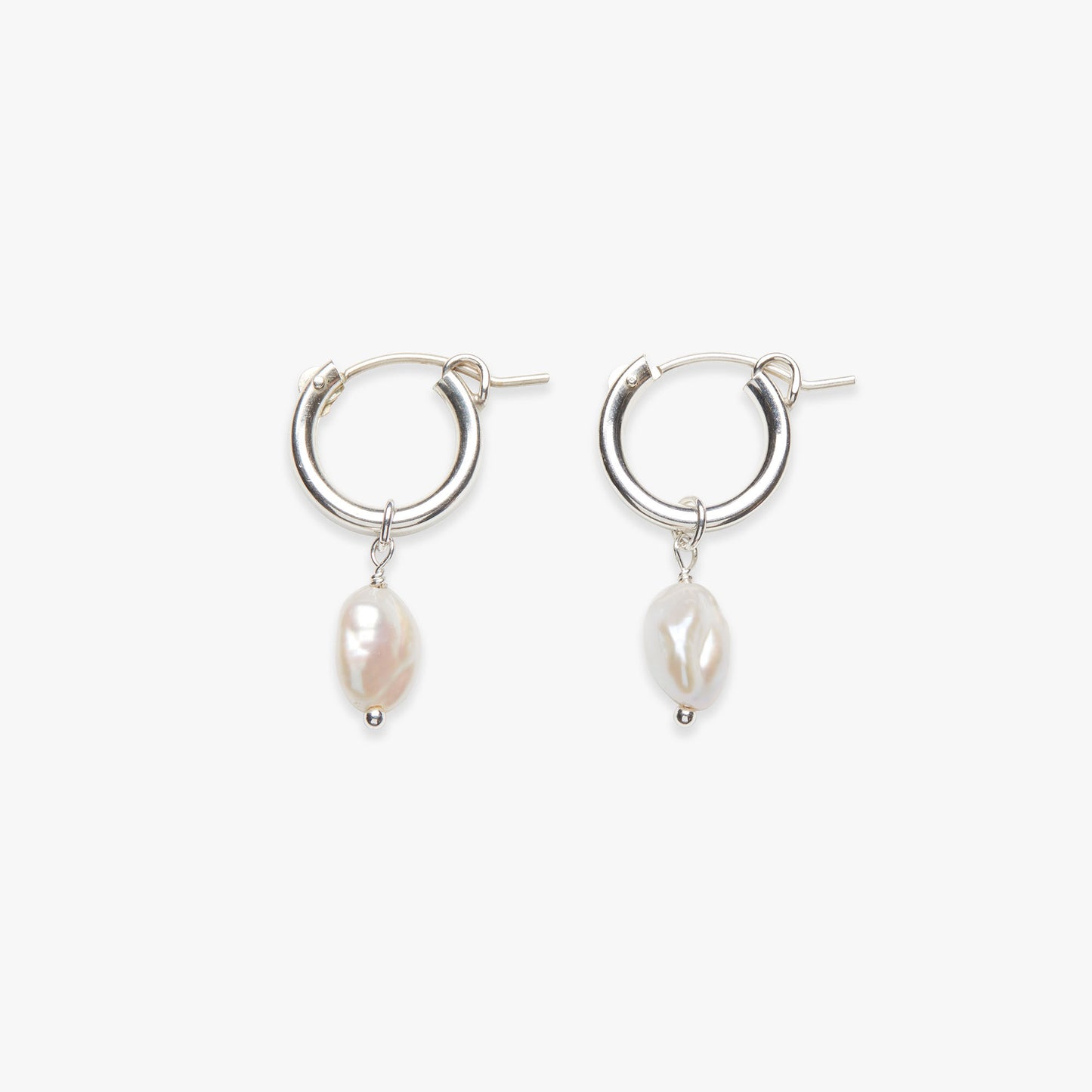 Silver hoop earrings with pearl drops on a white background
