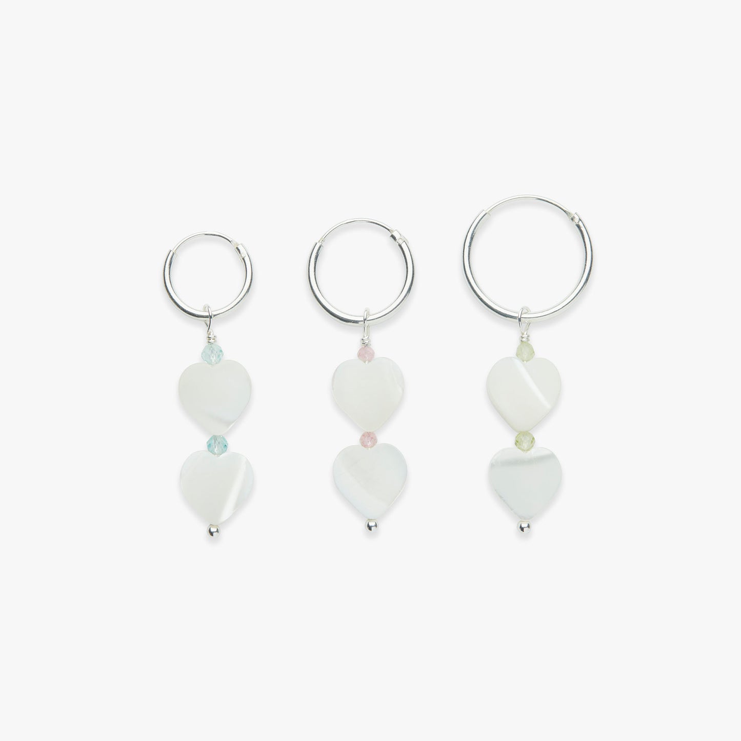 A set of three sterling silver hoop earrings with heart-shaped mother of pearl and gemstone accents, inspired by the Powerpuff Girls.