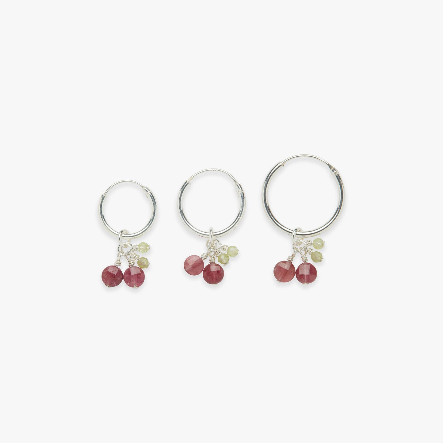Three silver hoop earrings with red and green gemstones on a white background
