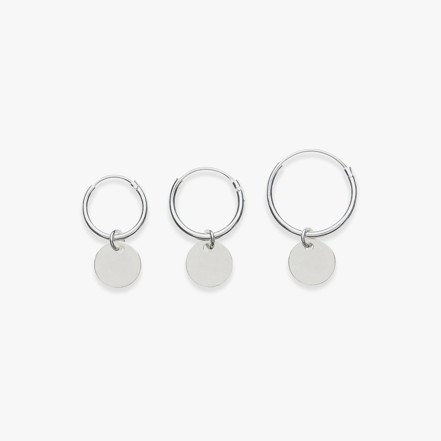 Three silver hoop earrings with round tags on a white background