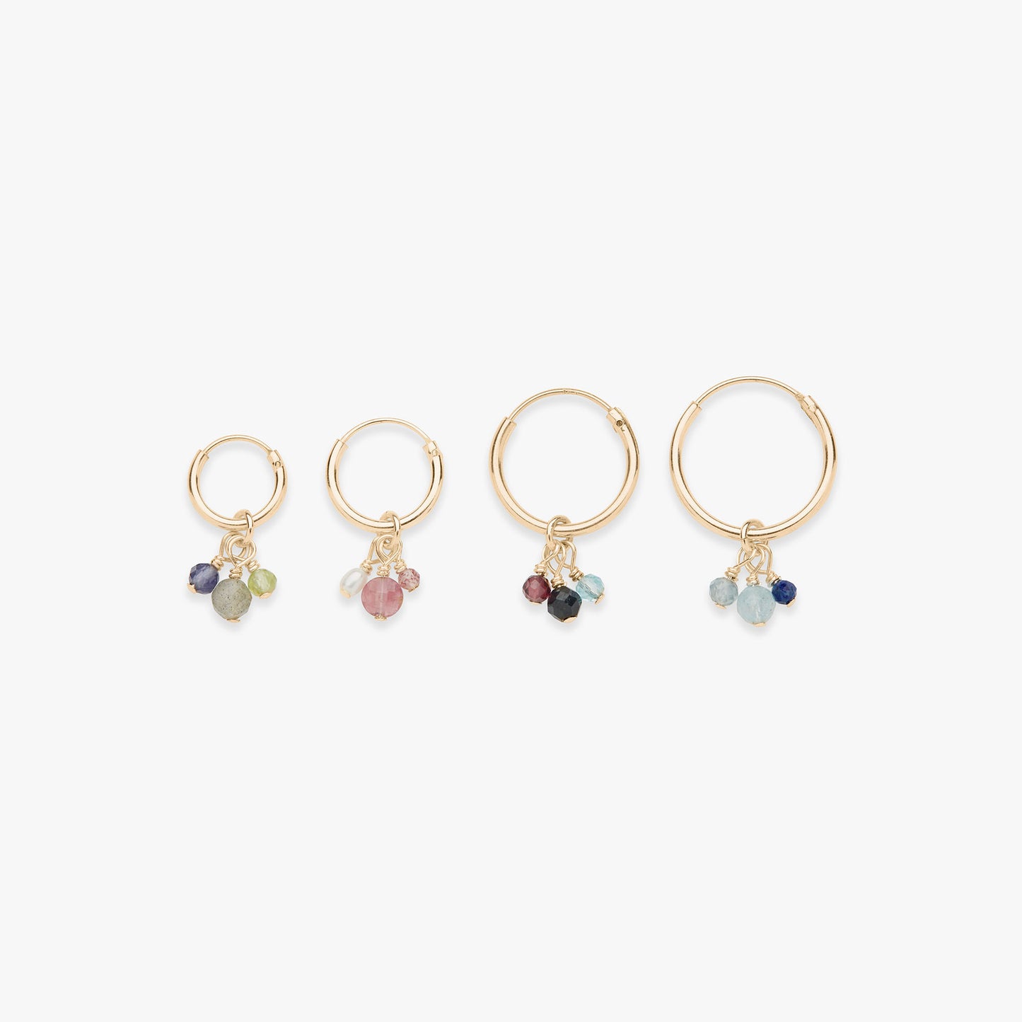 Set of four gold hoop earrings with gemstone charms on a white background