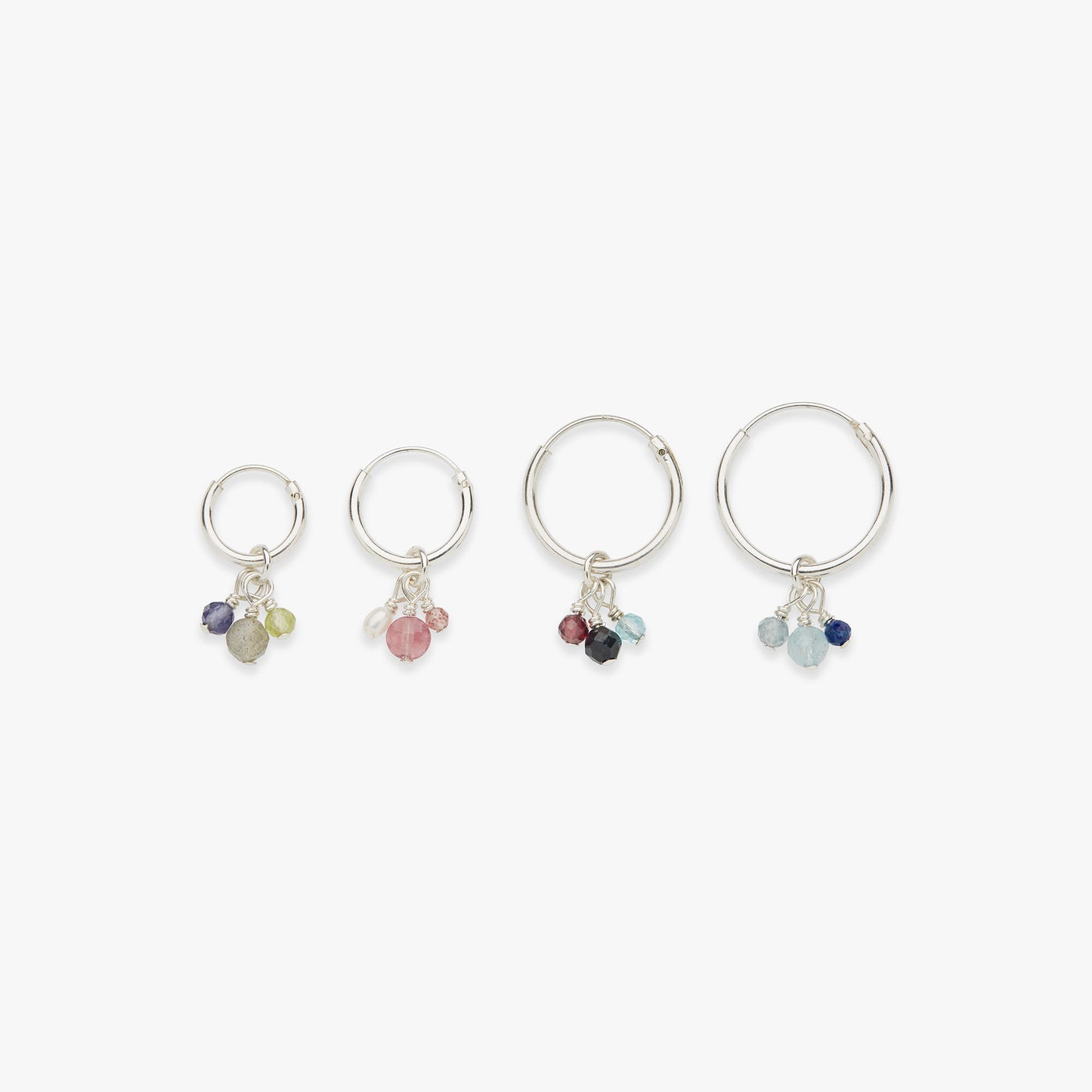 Set of four silver rings with colorful gemstones on a white background