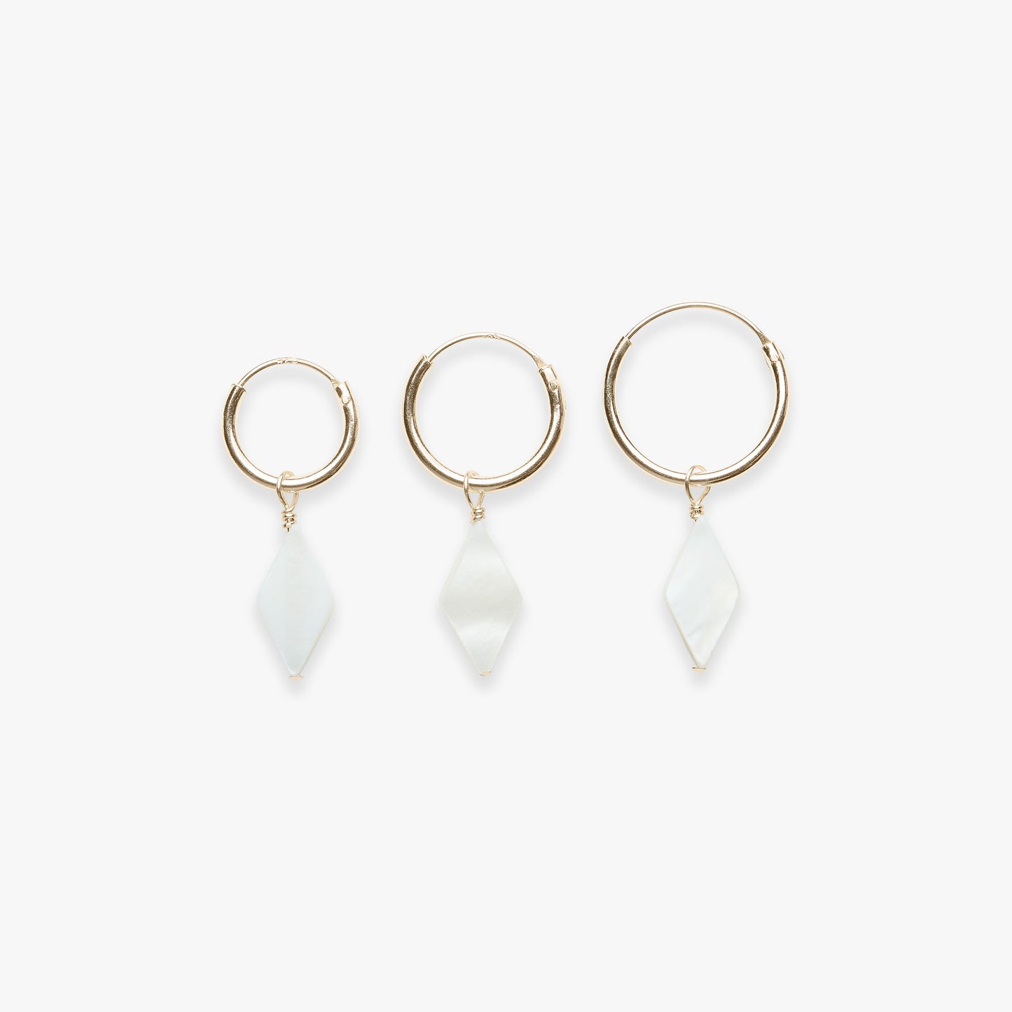 Three gold hoop earrings with white stone drops on a white background
