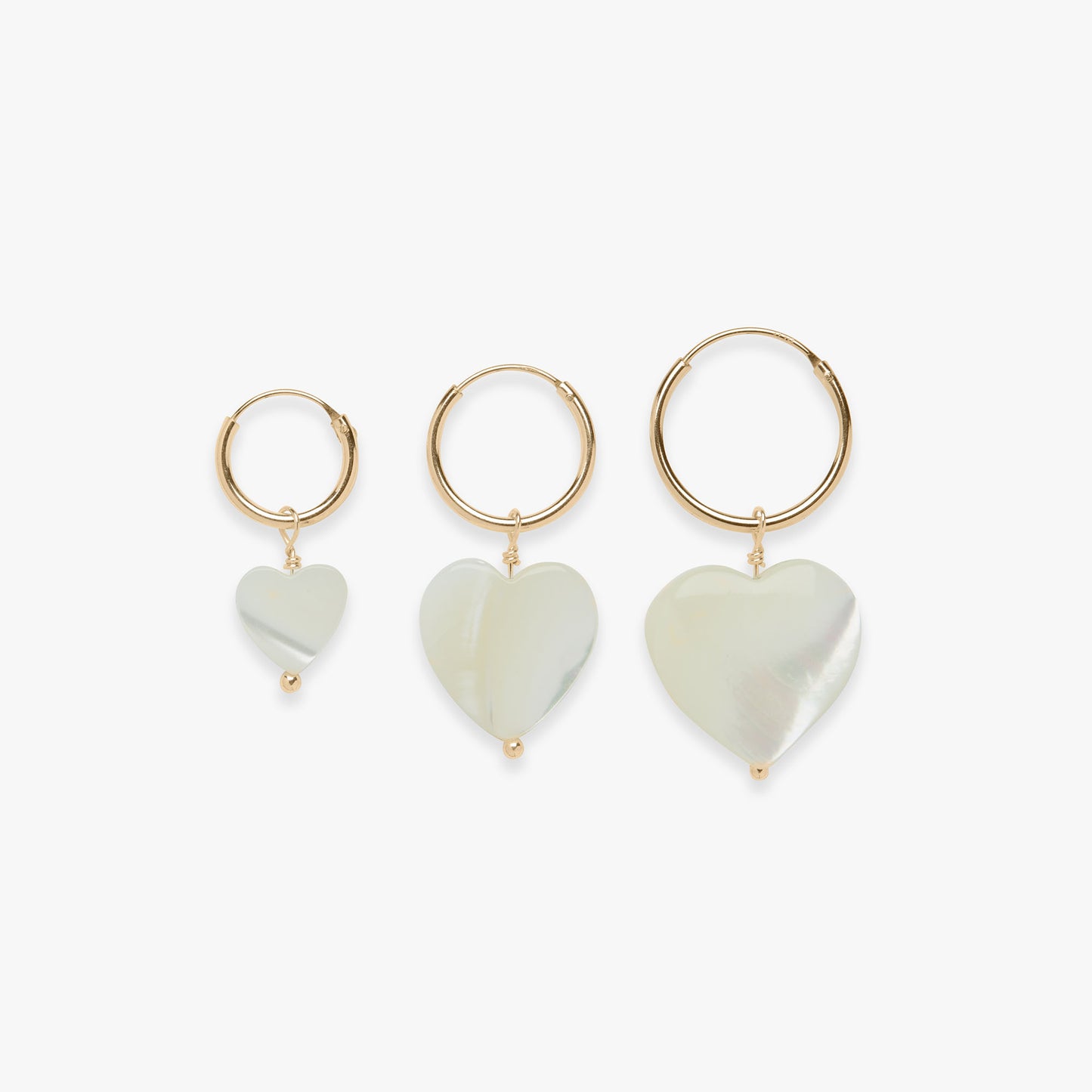 Three heart-shaped earrings with gold loops on a white background