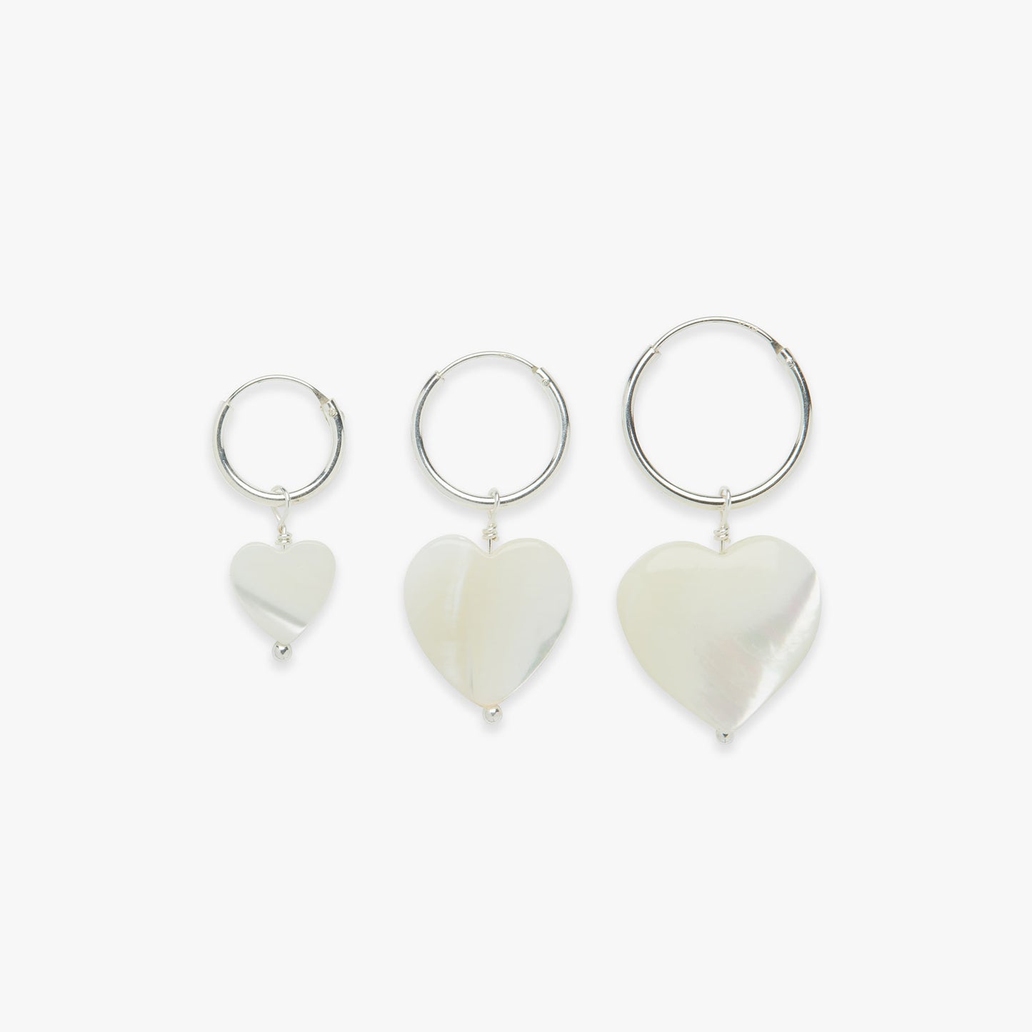 Three heart-shaped charm earrings on a white background