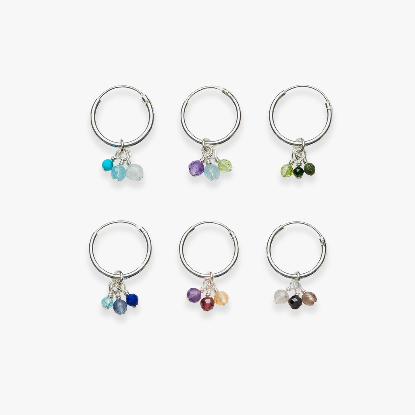 Set of six silver hoop earrings with multicolored beads on a white background