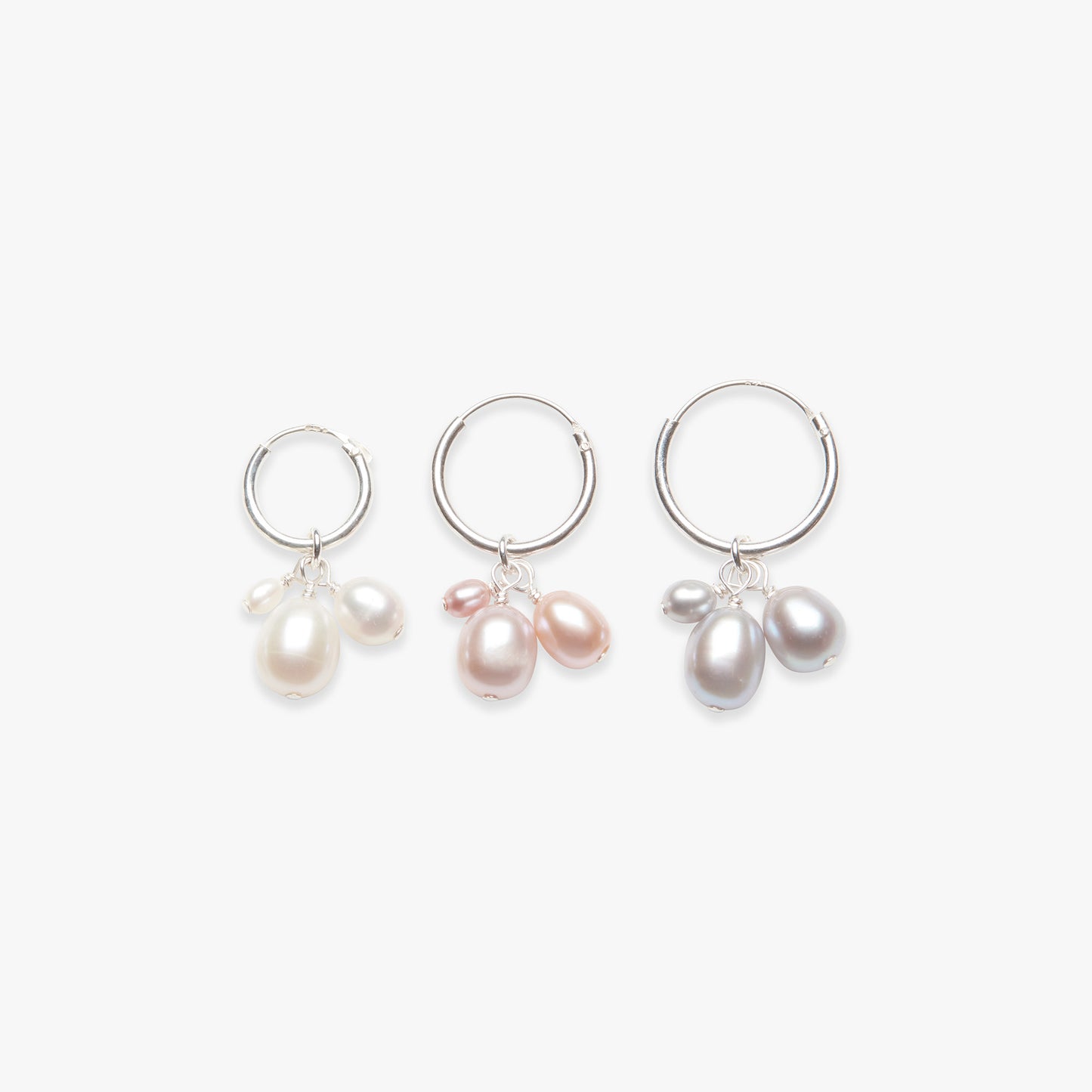 Three hoop earrings with pearl charms on a white background