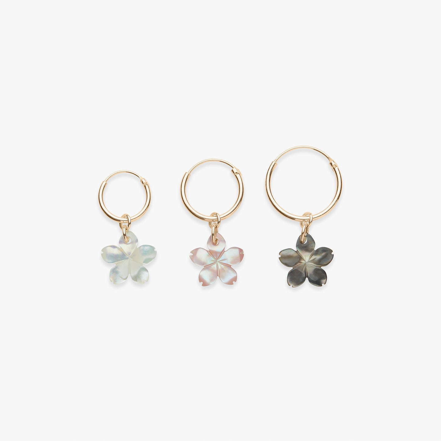 Three gold hoop earrings with floral charms on a white background