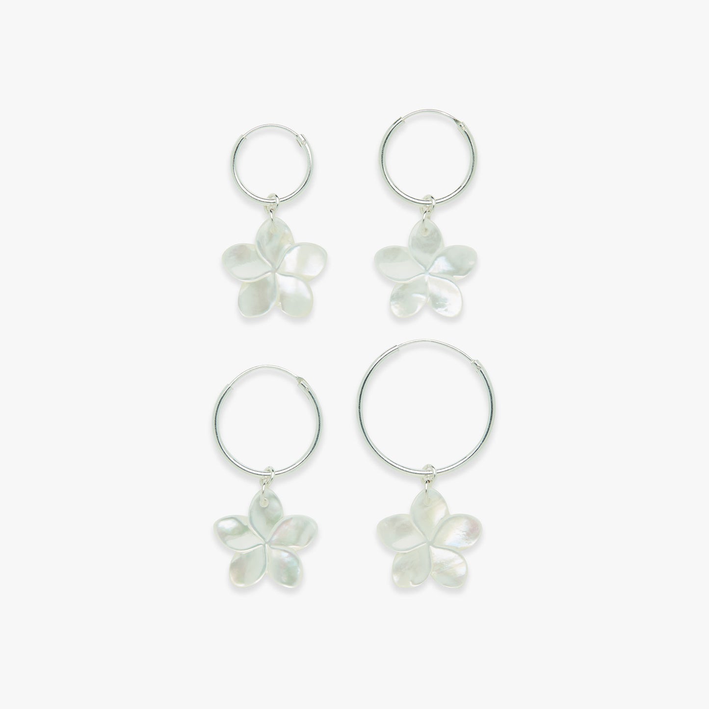 Set of four silver hoop earrings with floral charms on a white background
