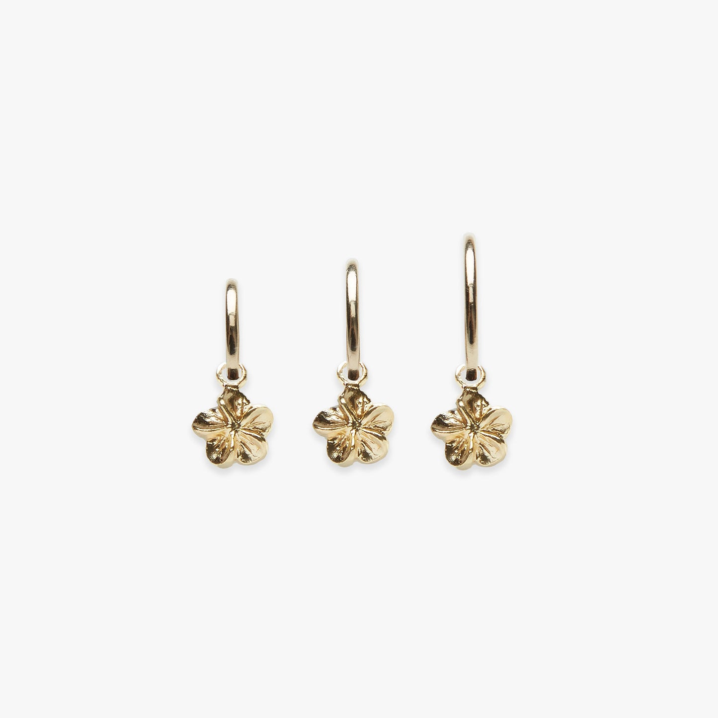 Three gold flower-shaped earrings on a white background