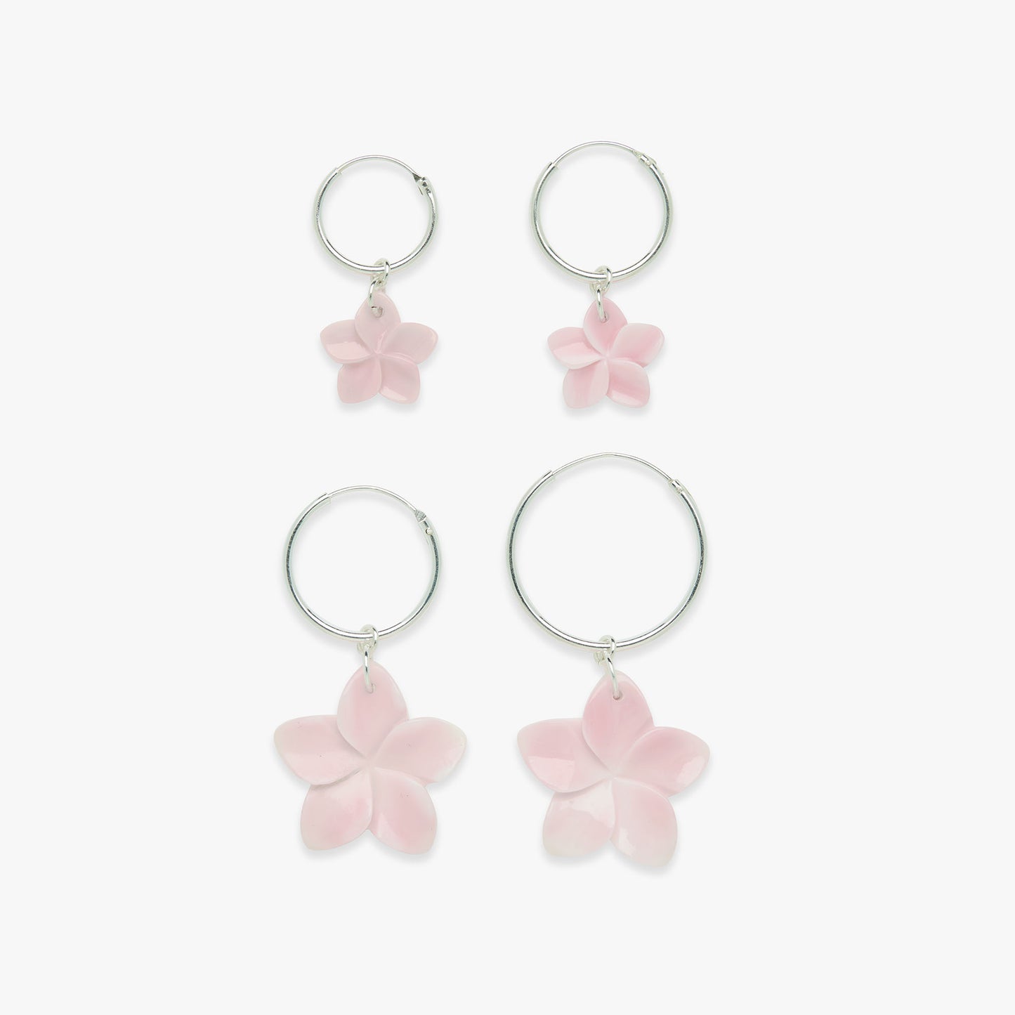 Set of hoop earrings with pink flower charms on a white background