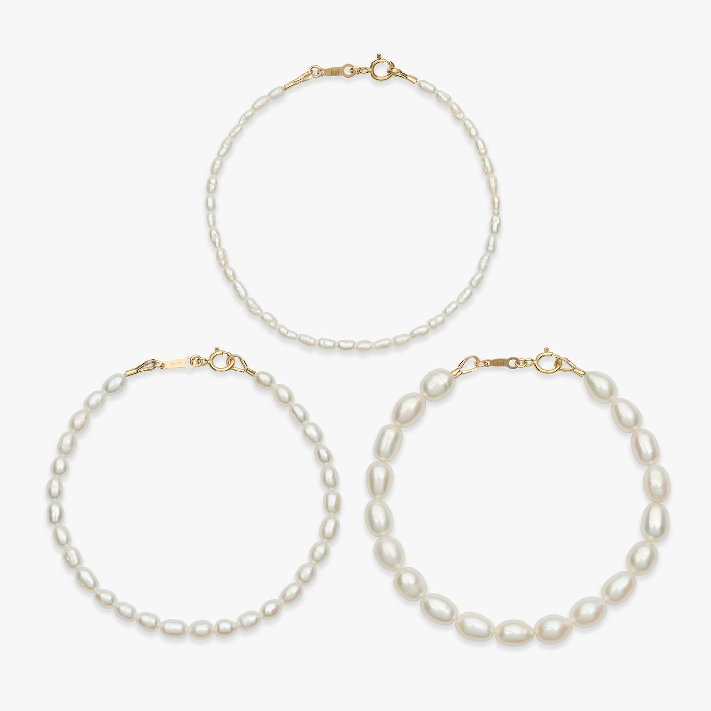 Three pearl jewelry pieces on a light gray background: one delicate necklace at the top and two larger hoop-style necklaces at the bottom, each with white pearls and gold-tone clasps.