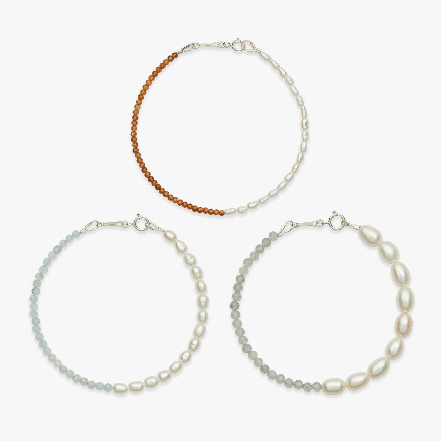 Three beaded bracelets arranged in a triangle on a light gray background. The top bracelet has a brown beaded section and a white pearl section.