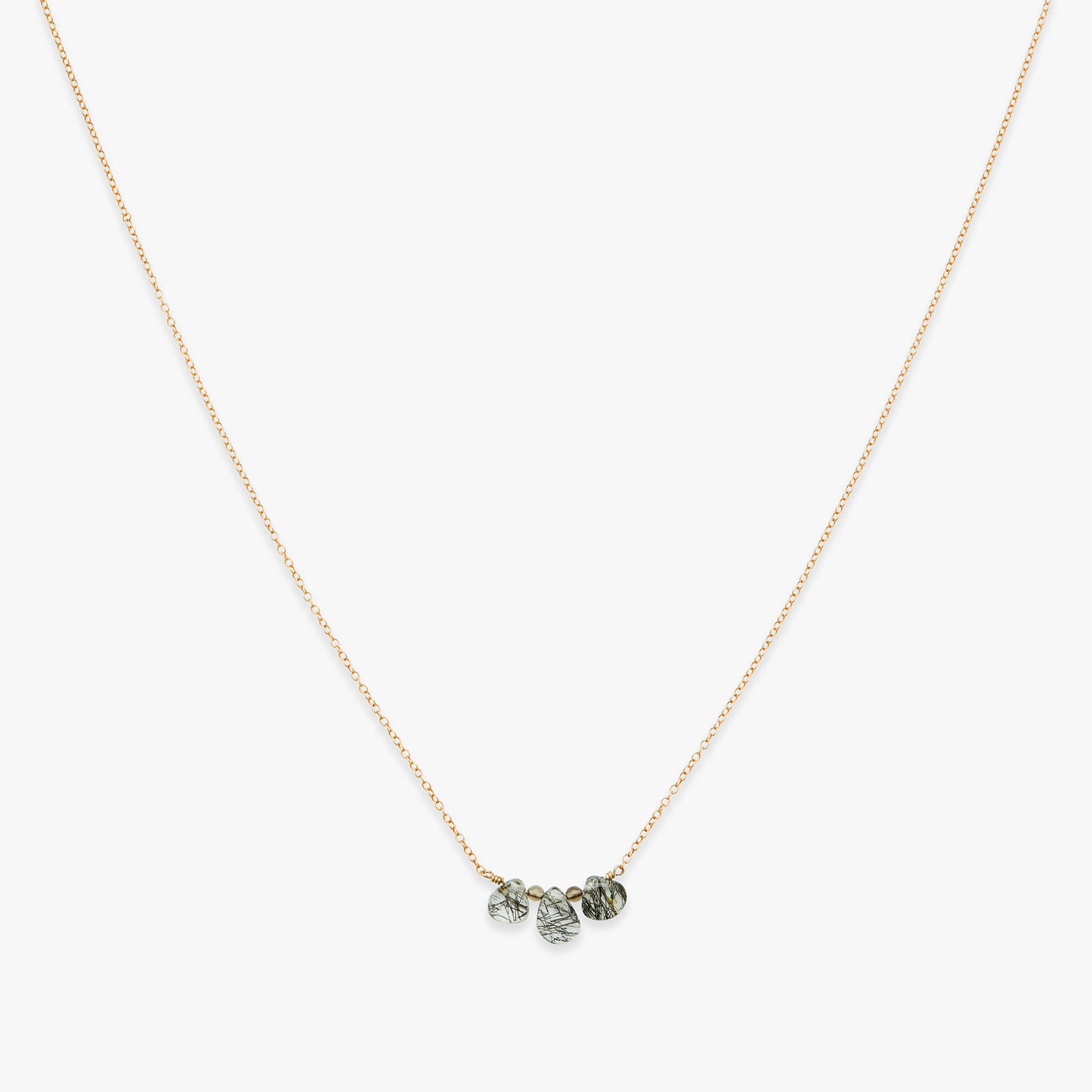 Necklace with three small round beads on a thin chain against a white background