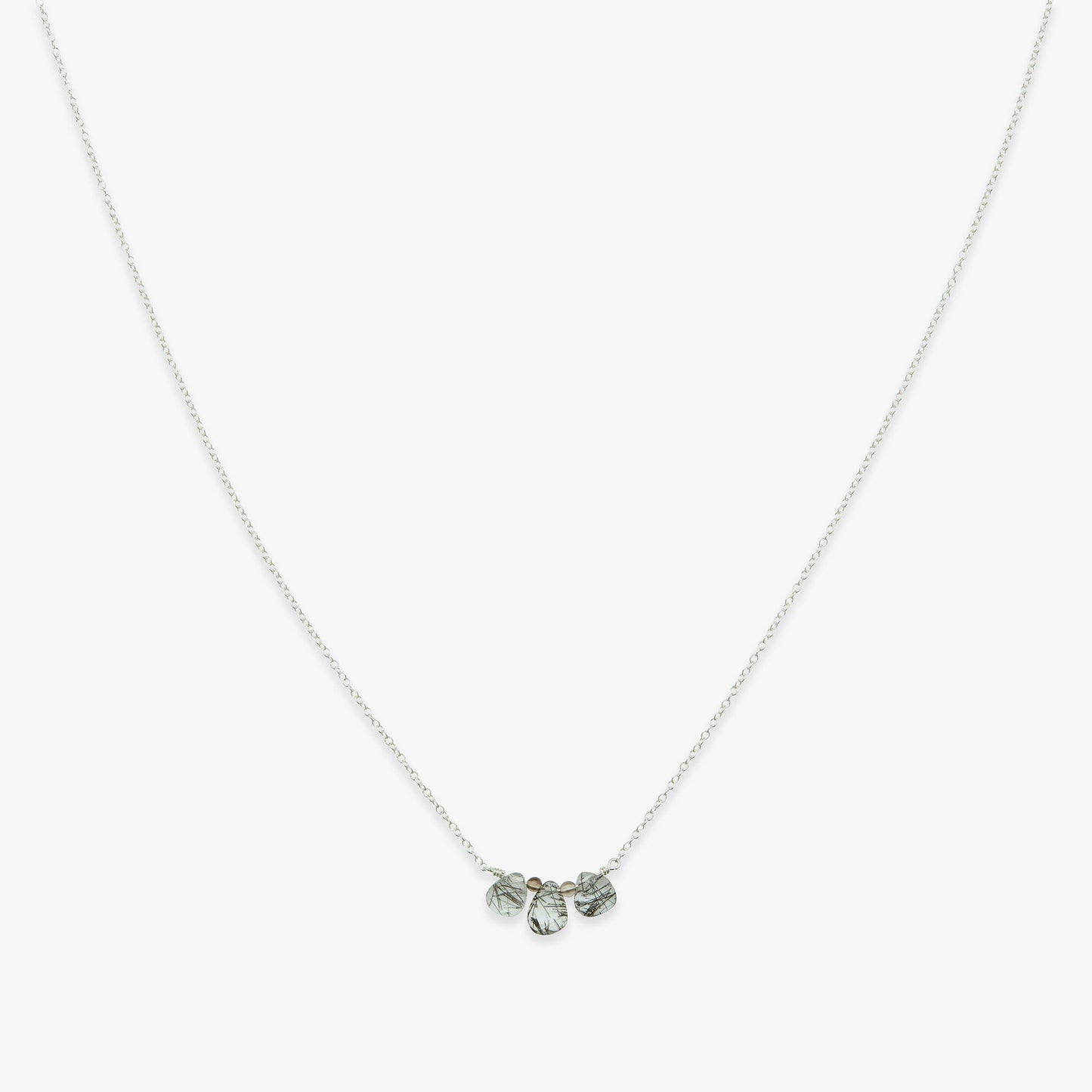 Silver necklace with three small pendants on a white background