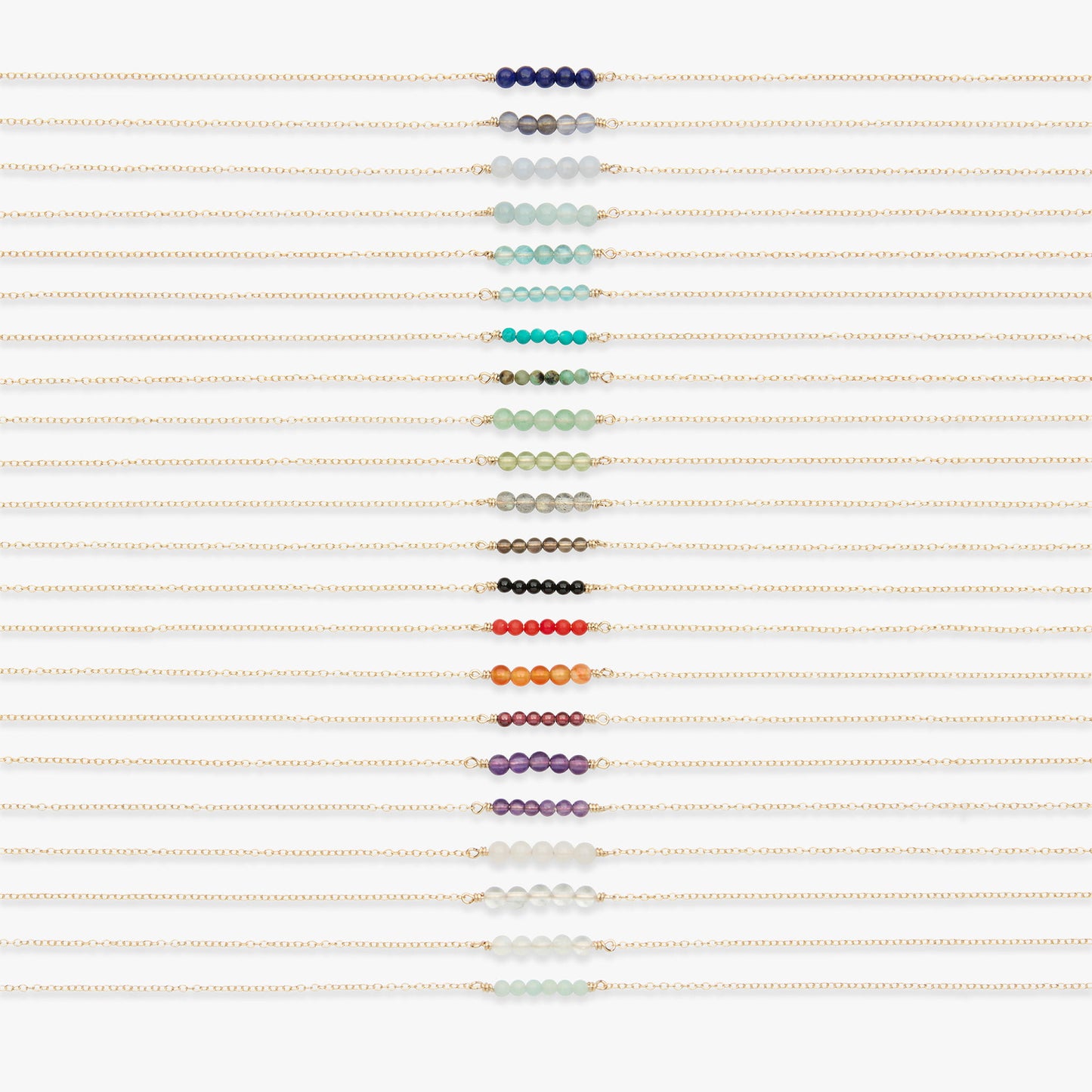 A vertical arrangement of multiple delicate gold bracelets, each adorned with a row of small round beads in different colors, displayed on a clean white background.